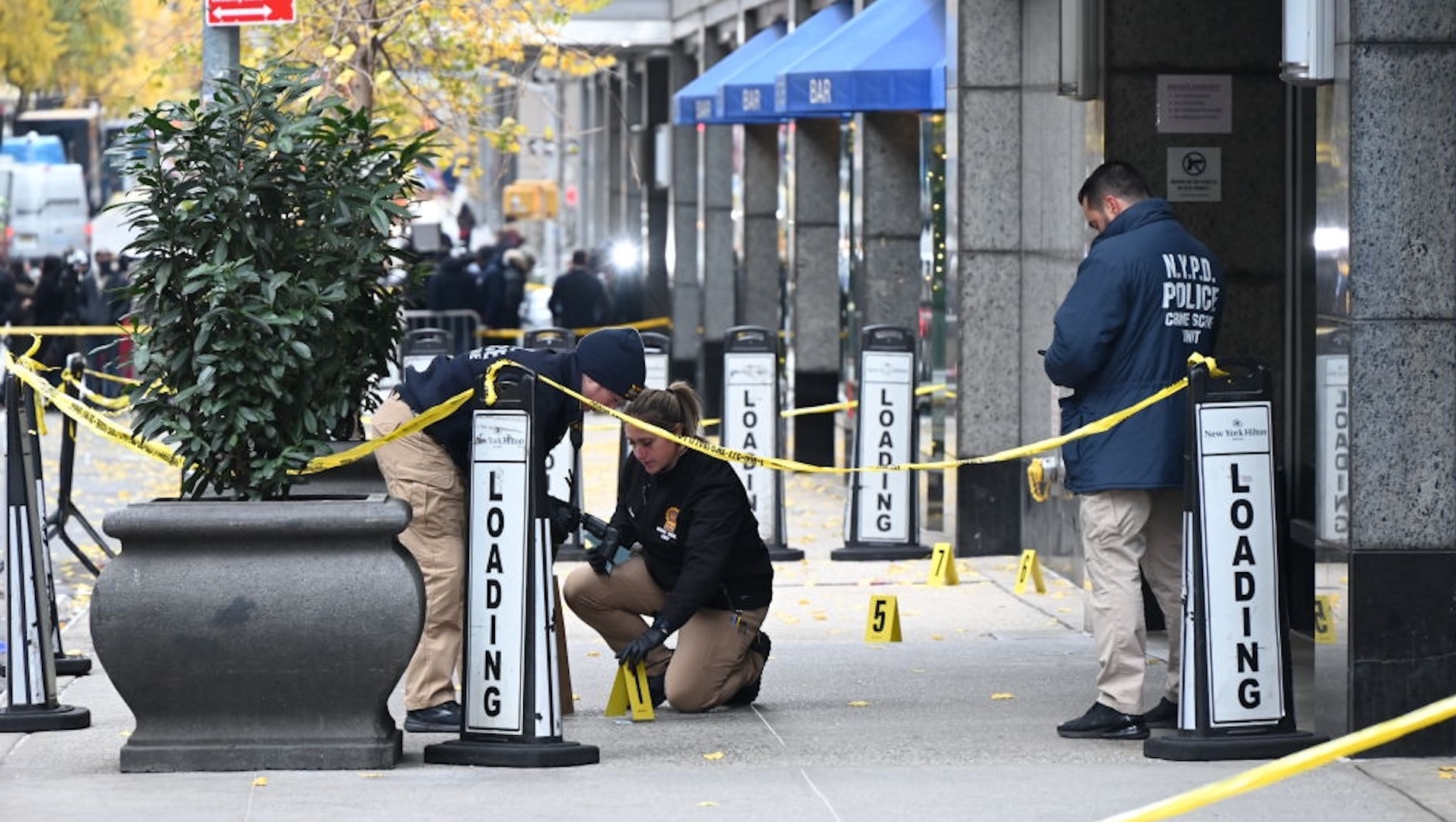 NEW YORK, UNITED STATES - DECEMBER 4: Police officers investigate the scene where UnitedHealthcare CEO Brian Thompson was fatally shot in Midtown Manhattan near a hotel on 54th Street between 6th and 7th Avenues on December 04, 2024 in New York, United States. UnitedHealthcare CEO Brian Thompson, 50, was fatally shot in what authorities are calling a 'brazen, targeted attack' outside the Hilton Hotel in Midtown Manhattan. The masked gunman, who waited several minutes before ambushing Thompson, fired multiple times, striking him in the back and right calf. Thompson was rushed to Roosevelt Hospital but succumbed to his injuries. The suspect fled the scene and remains at large. A $10,000 reward has been offered for information leading to his arrest.