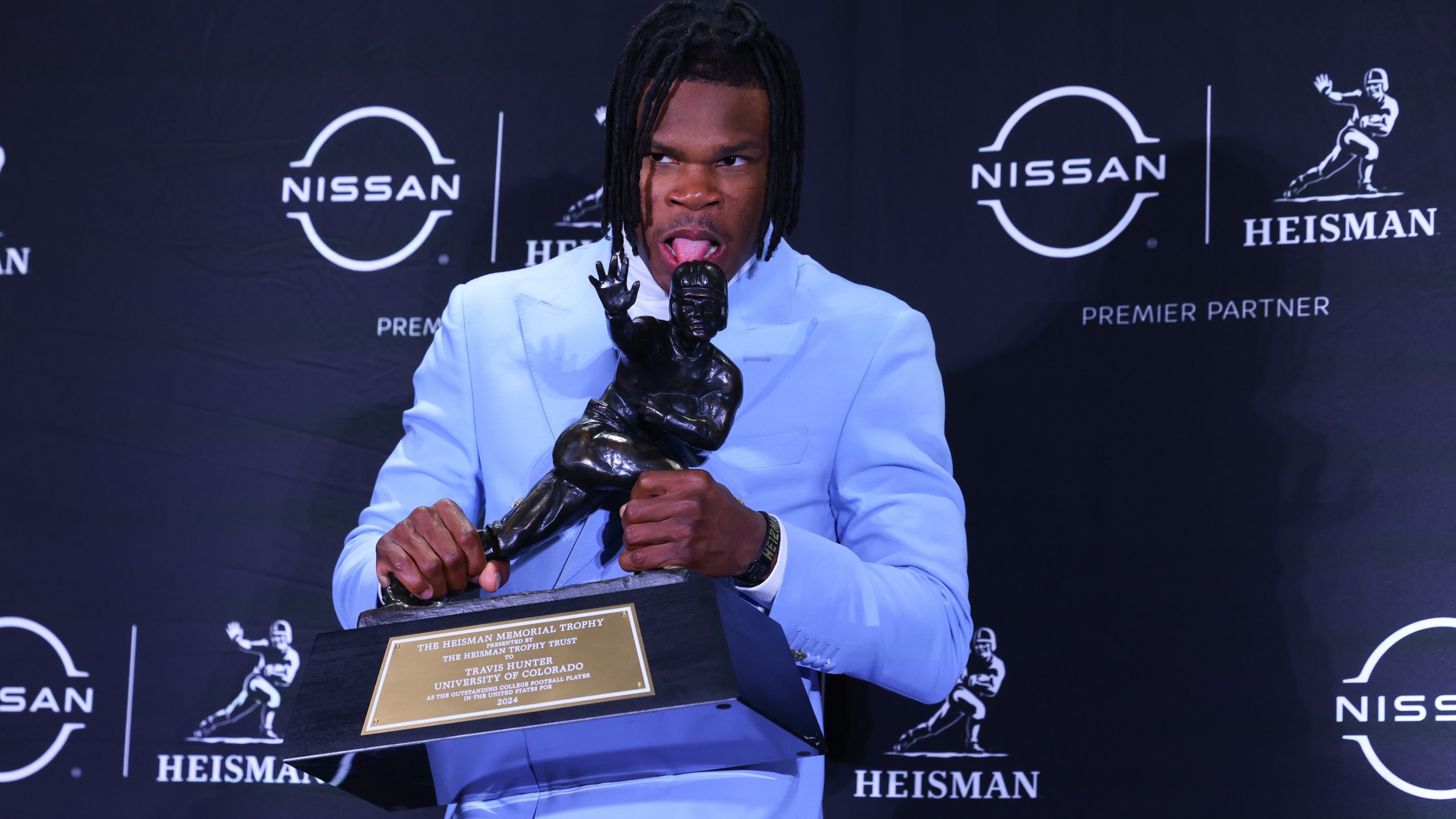 Travis Hunter University of Colorado cornerback/wide receiver puts his tongue on the Trophy during the Heisman Trophy press conference at the Marriott Marquis on December 14, 2024.