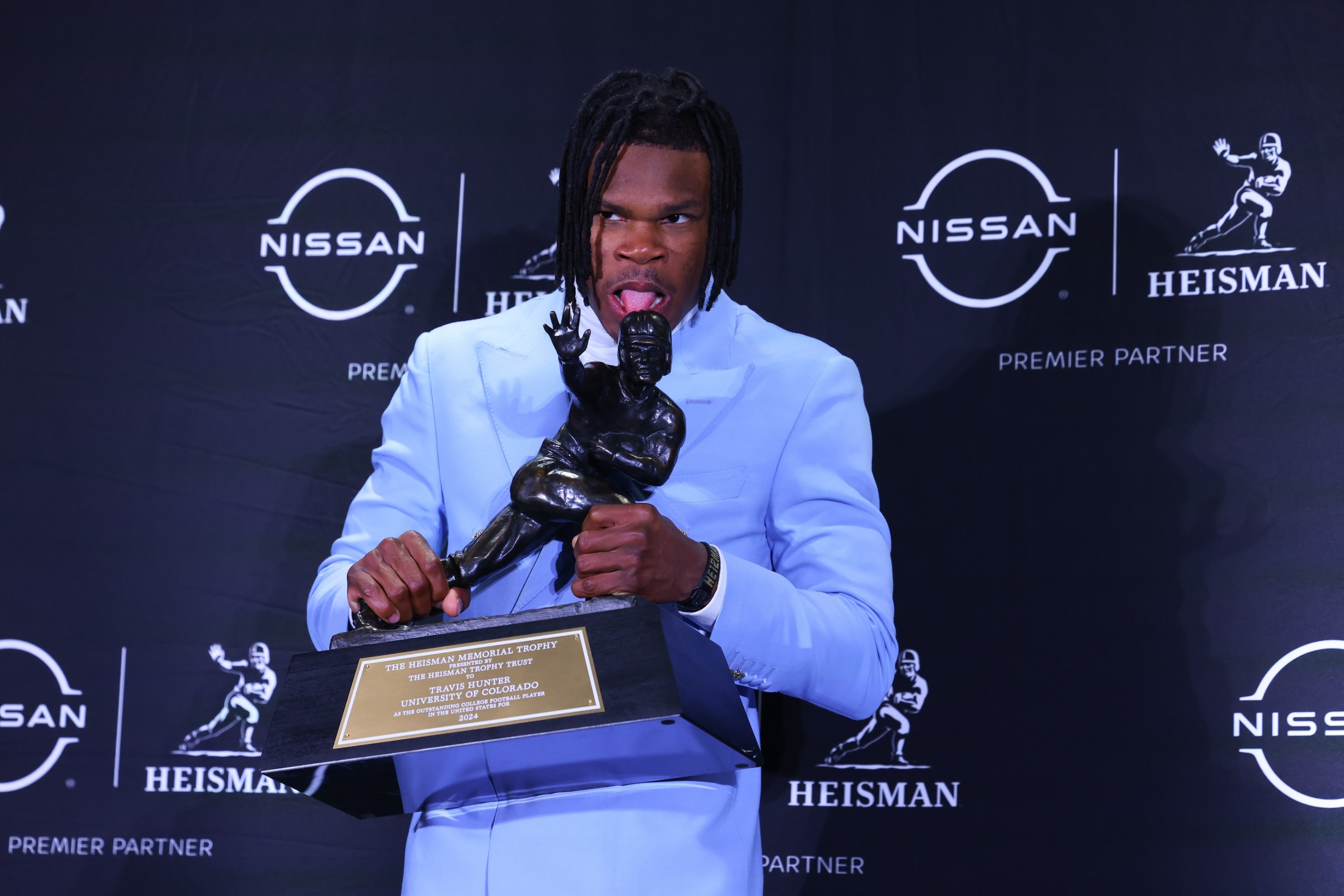 Travis Hunter University of Colorado cornerback/wide receiver puts his tongue on the Trophy during the Heisman Trophy press conference at the Marriott Marquis on December 14, 2024.