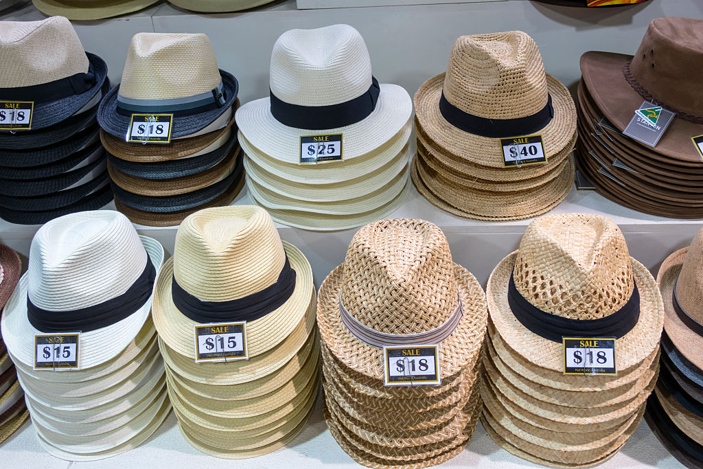 A collection of straw hats and fedoras for sale at a market