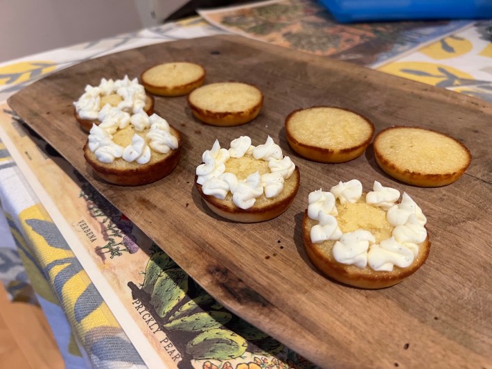 White cream-cheese icing and yellow lemon curd piped onto four small baked sponges.