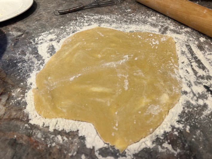 Tart dough, showing smears of butter, rolled out flat on a floured countertop.