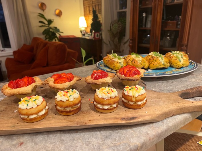 Four mini sandwiches, four tarts, and four egg-salad sandwiches sit together on a countertop.