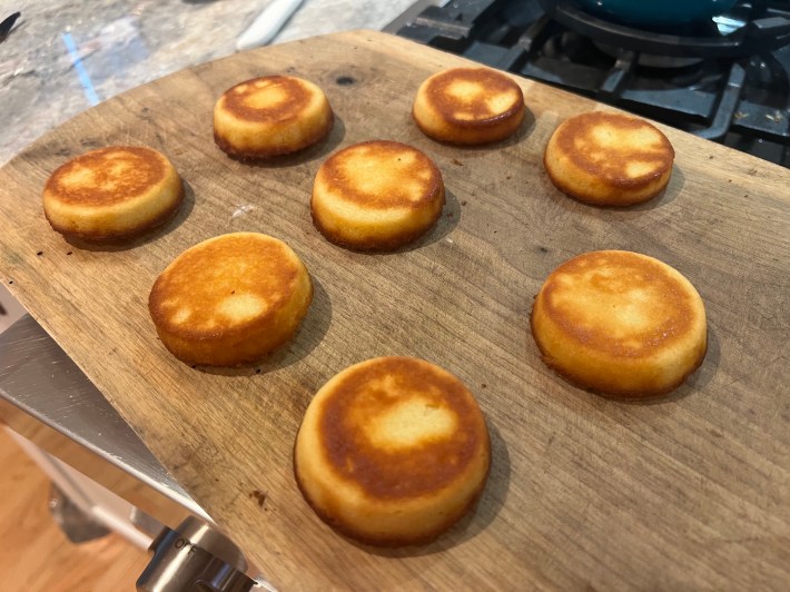 Eight baked mini sponges, turned out onto a wooden cutting board.