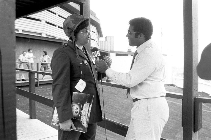 Bryant Gumbel interviews Chicago DJ Steve Dahl, holding a disco record and wearing military style clothing, during an interview prior to the anti-disco promotional event Disco Demolition Night, held at Comiskey Park, in between games of a nighttime doubleheader between the Chicago White Sox and the Detroit Tigers, Chicago, Illinois, July 12, 1979.