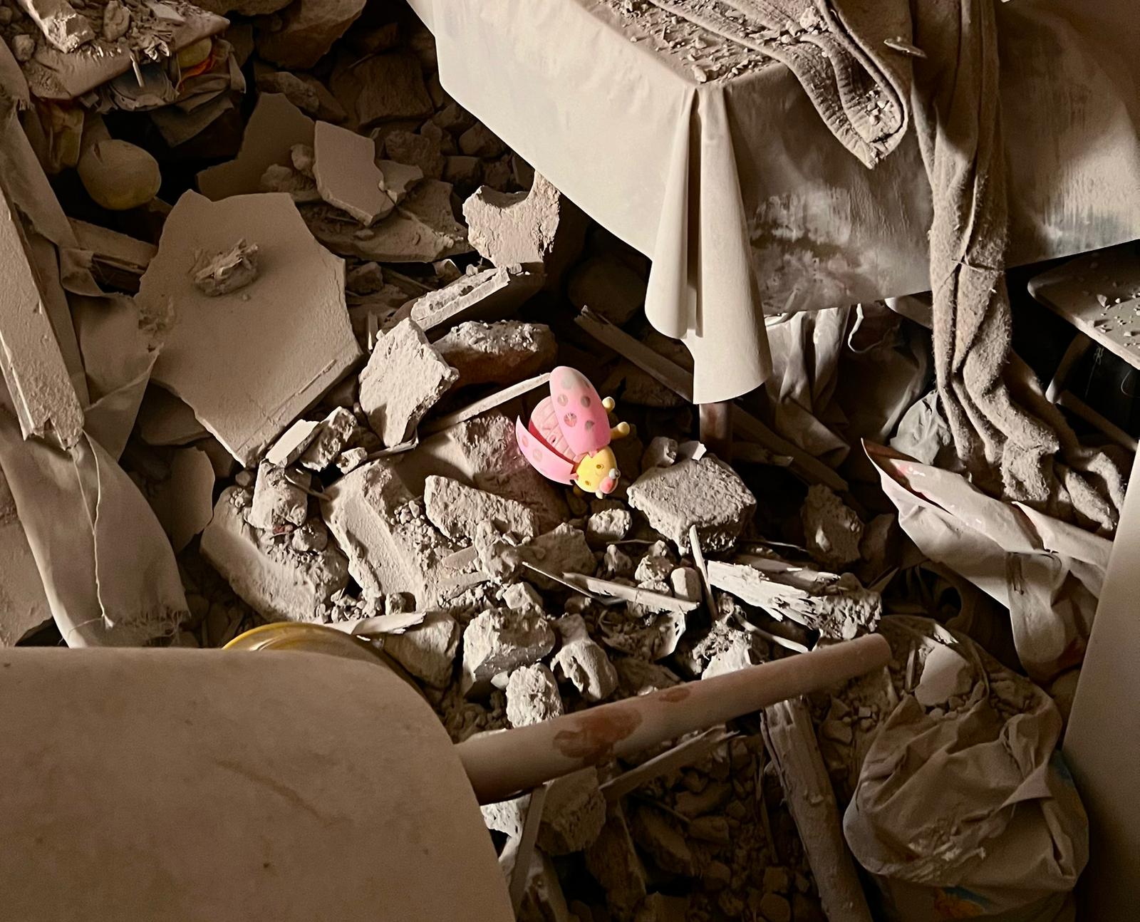 The rubble of the author's house in Gaza. A child's toy is visible.