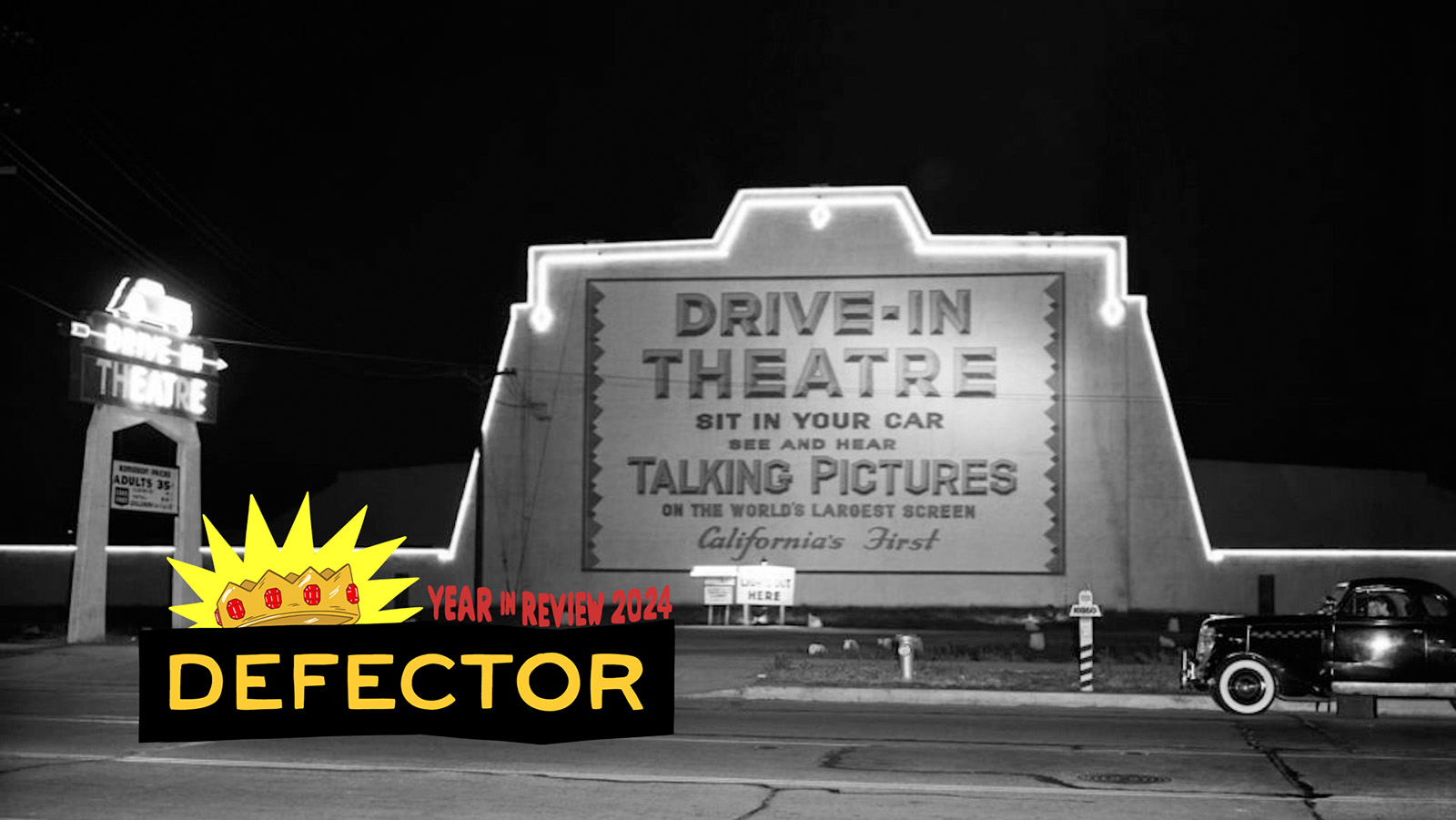 An old timey drive-in, with an old-timey pickup truck in front of it. The front of the drive in says "DRIVE-IN THEATRE. SIT IN YOUR CAR. SEE AND HEAR TALKING PICTURES. ON THE WORLD'S LARGEST SCREEN. Californa's First." There's also a neon entrance sign. The photo is black and white. The Year in Review Defector graphic is at the bottom.