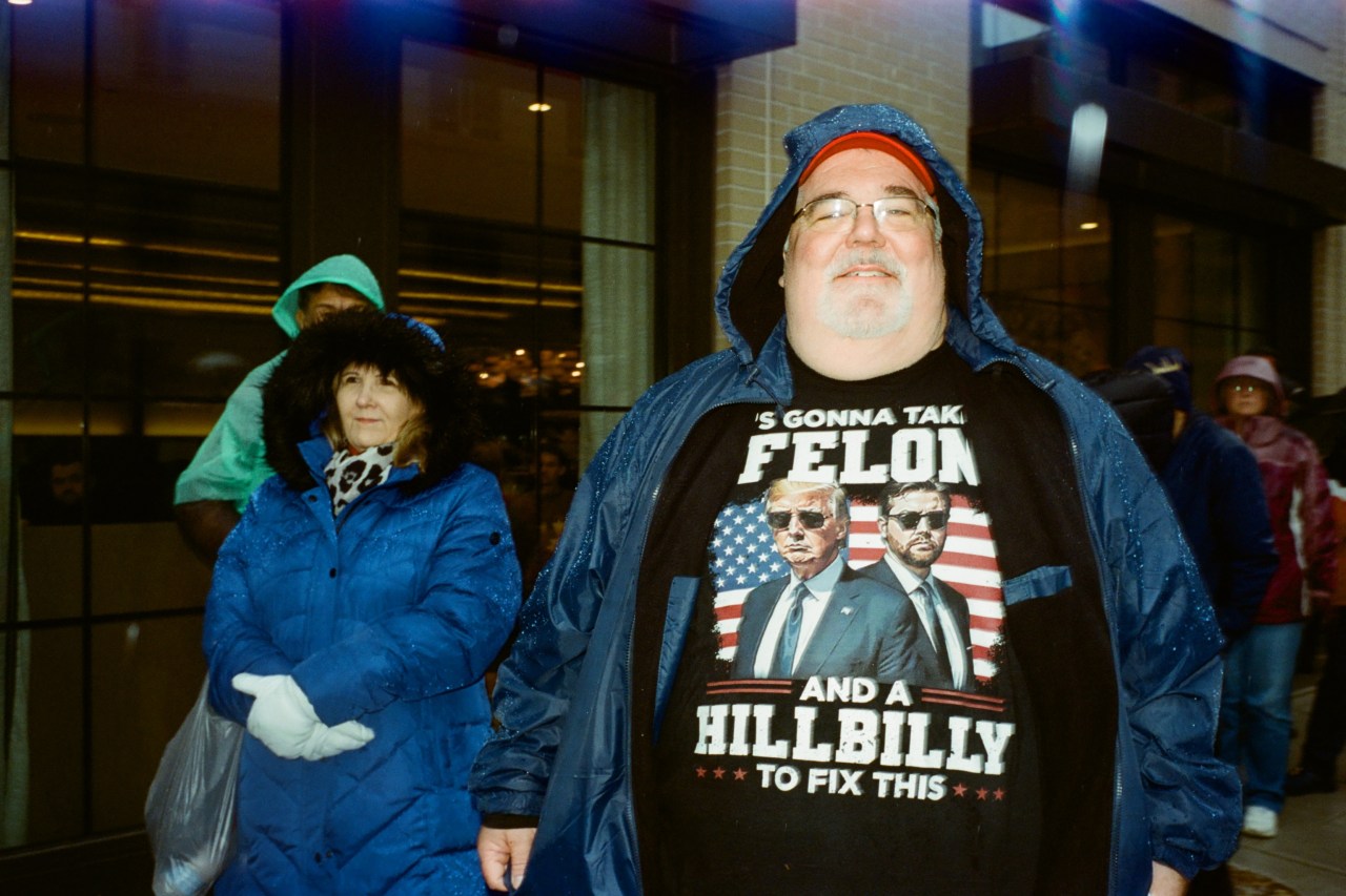 A man waits in line with a Donald Trump and JD Vance t-shirt