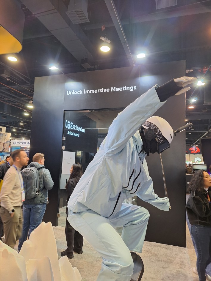 A mannequin kind of freestyling on a unicycle type thing in front of a sign that reads Unlock Immersive Meetings at the 2025 CES.