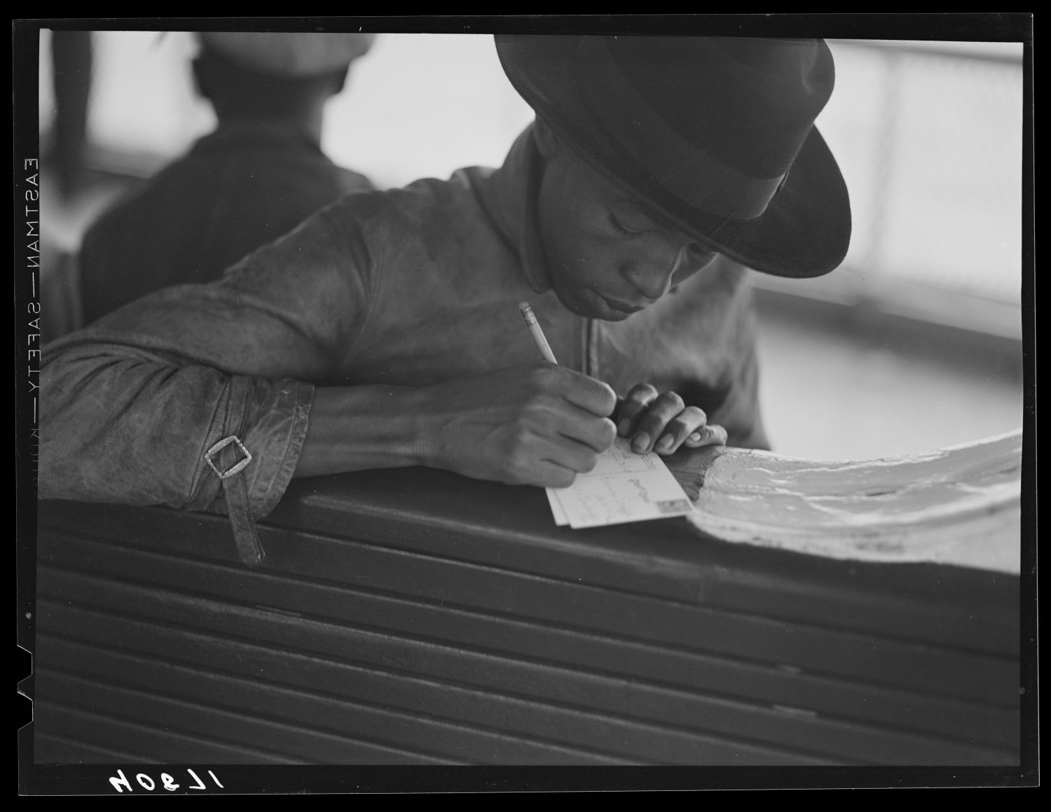 Black-and-white photo of a writer scrawling on paper.