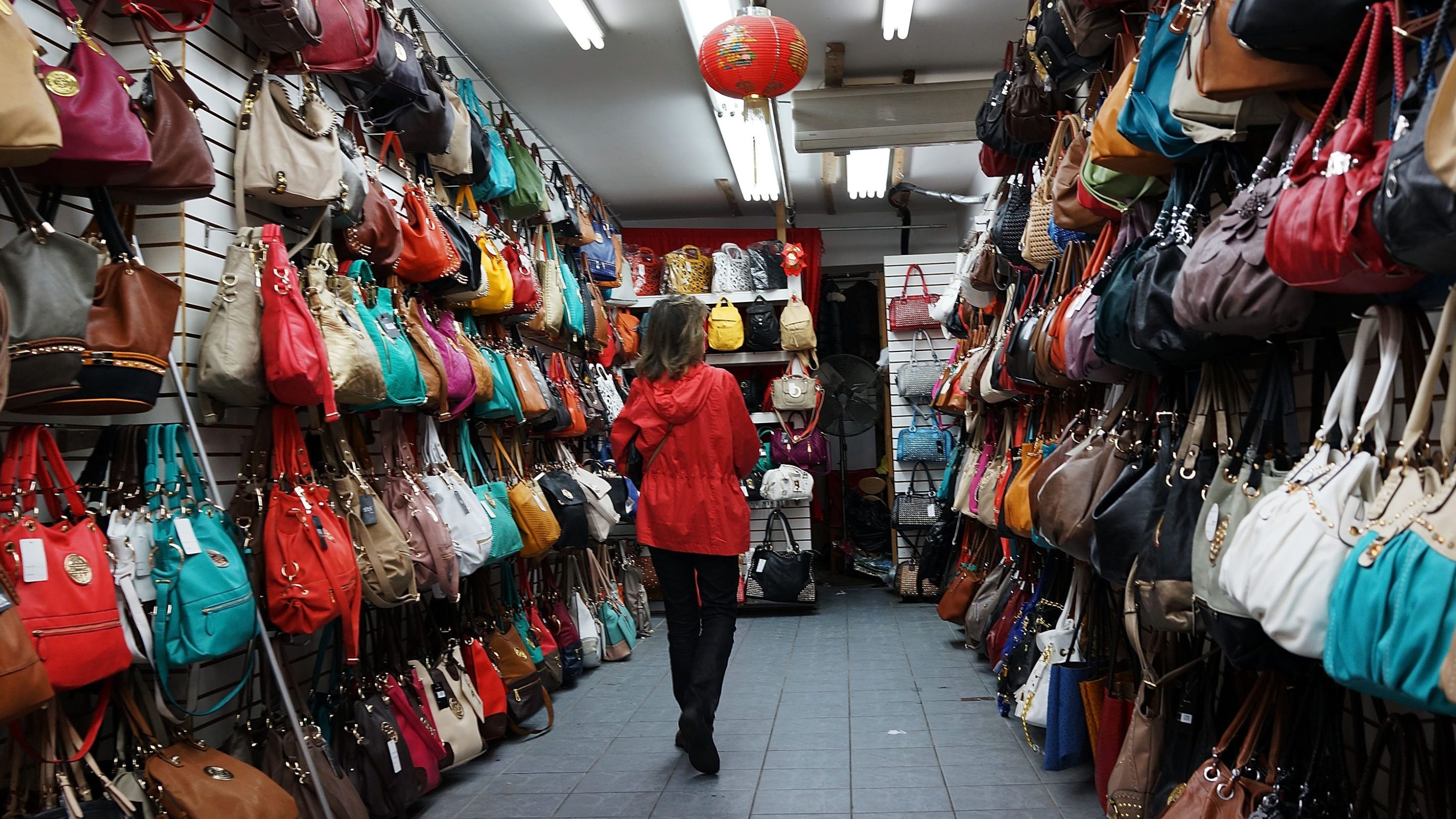 Fashionable women's bags hang along the sidewalk storefronts on Canal Street in New York City.