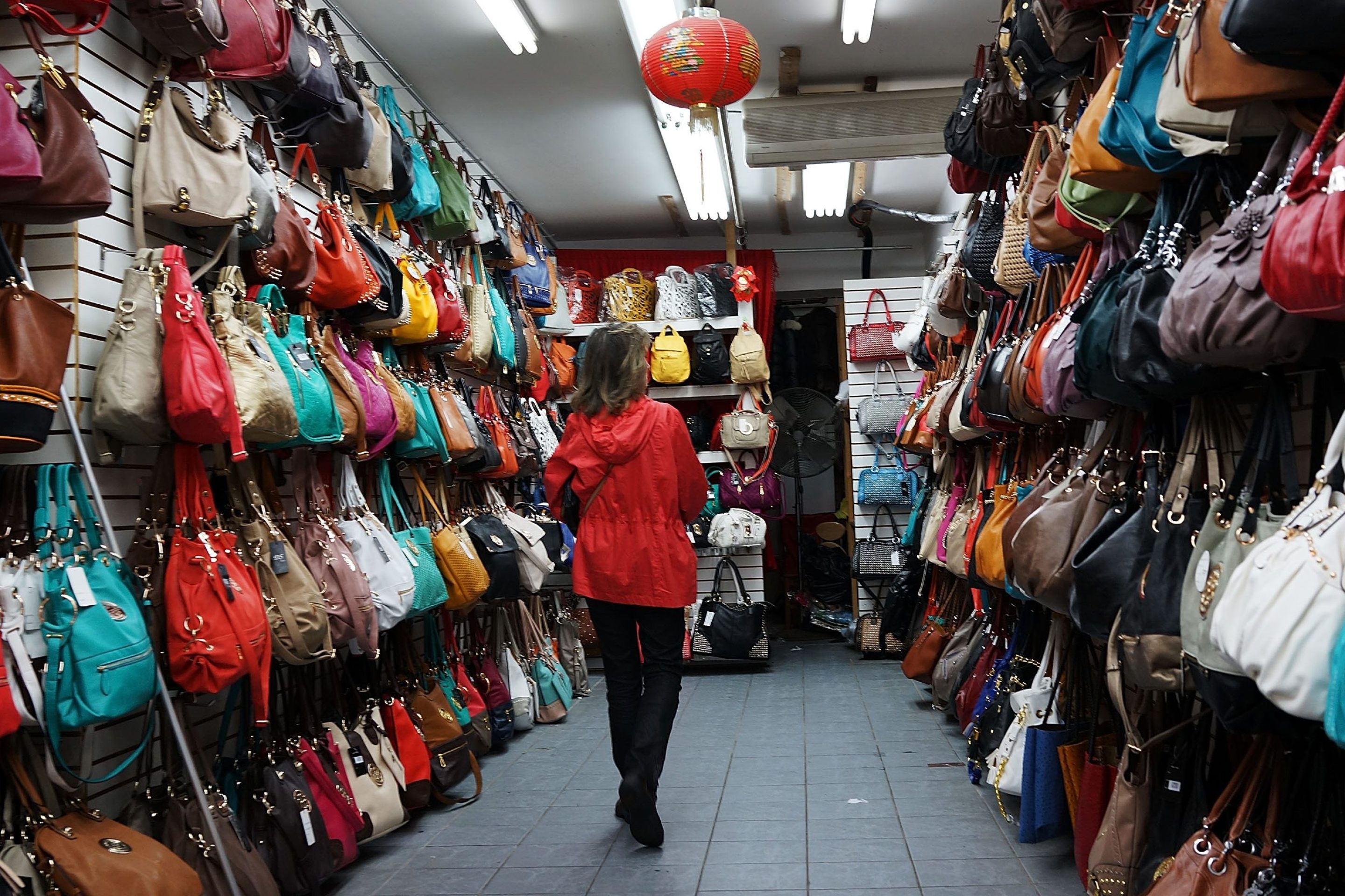 Fashionable women's bags hang along the sidewalk storefronts on Canal Street in New York City.