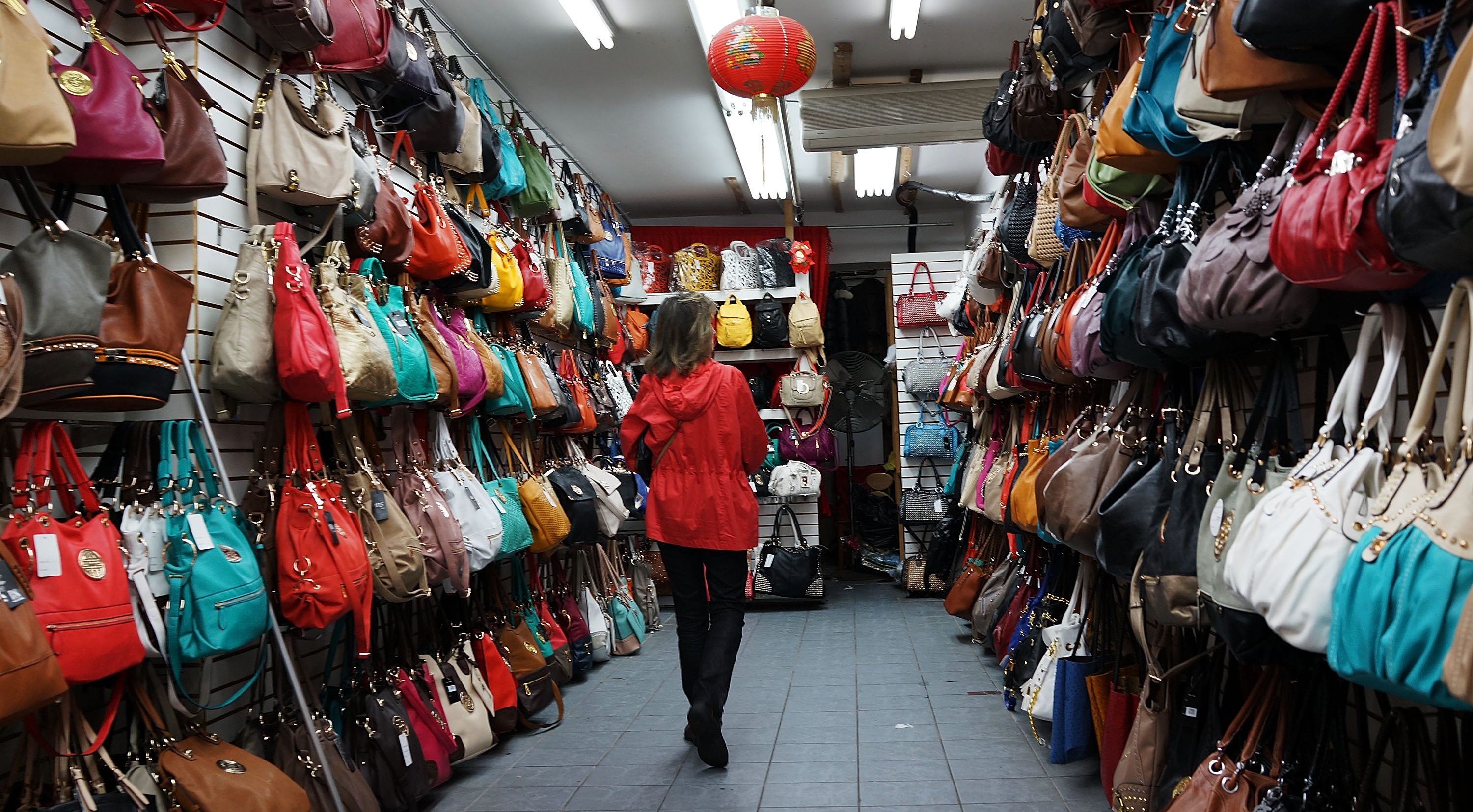 Fashionable women's bags hang along the sidewalk storefronts on Canal Street in New York City.
