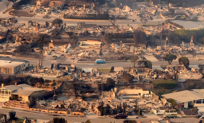 In this aerial view taken from a helicopter a blue van sits intact amid burned homes seen from above during the Palisades fire near the Pacific Palisades neighborhood of Los Angeles, California on January 9, 2025. Massive wildfires that engulfed whole neighborhoods and displaced thousands in Los Angeles remained totally uncontained January 9, 2025, authorities said, as US National Guard soldiers readied to hit the streets to help quell disorder. Swaths of the United States' second-largest city lay in ruins, with smoke blanketing the sky and an acrid smell pervading almost every building.