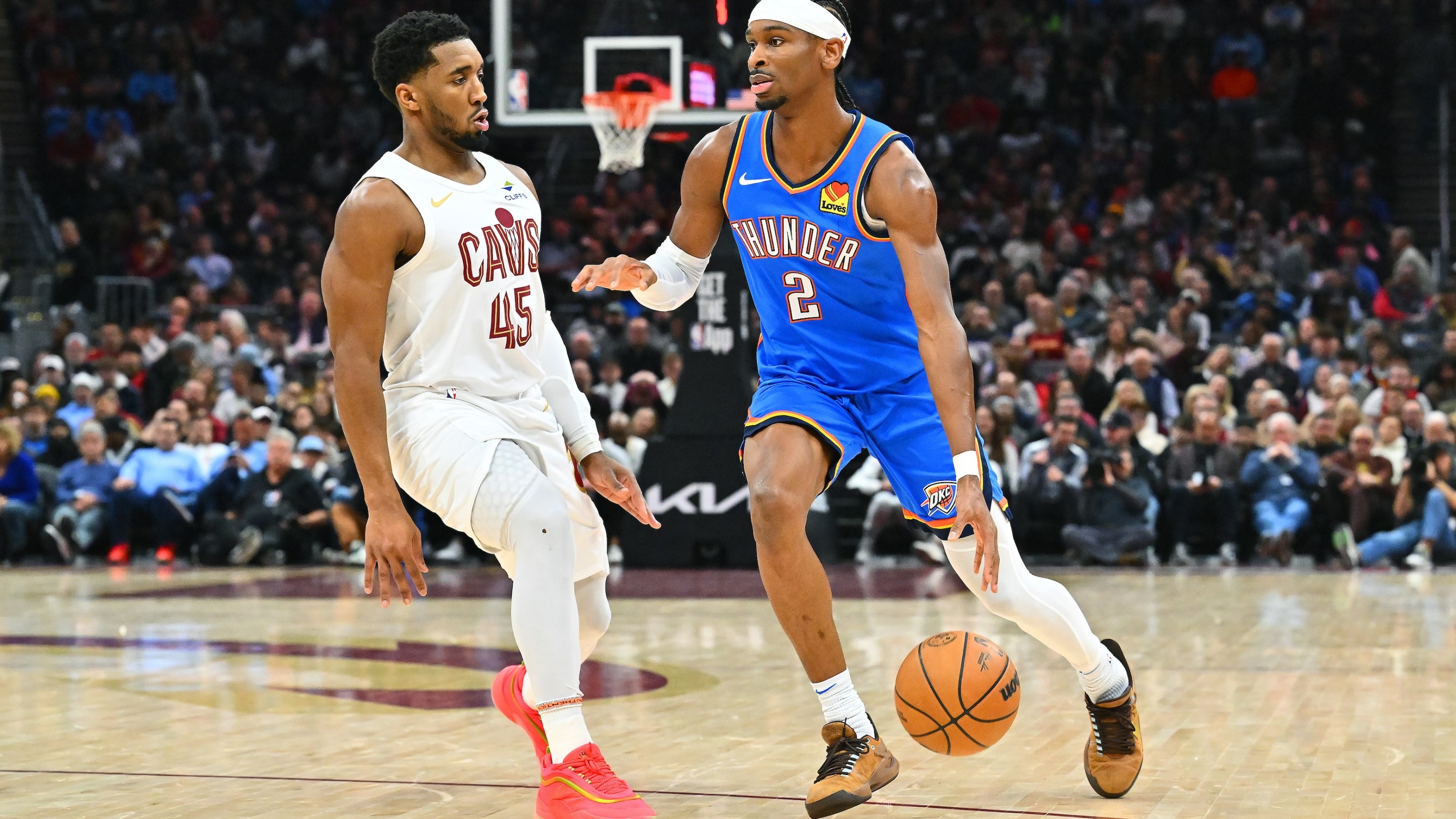 Shai Gilgeous-Alexander of the Oklahoma City Thunder drives to the basket around Donovan Mitchell of the Cleveland Cavaliers at Rocket Mortgage Fieldhouse.