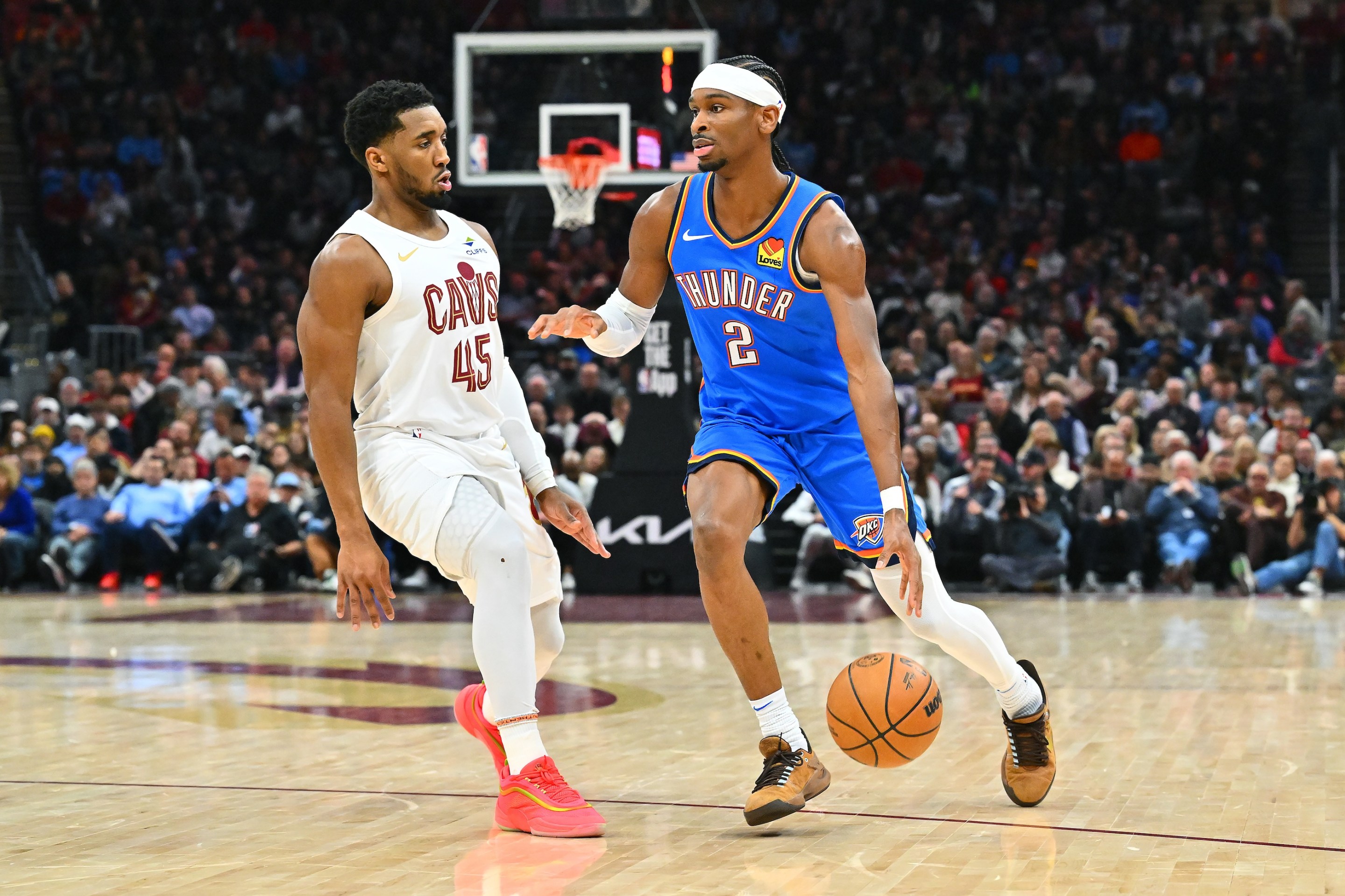 Shai Gilgeous-Alexander of the Oklahoma City Thunder drives to the basket around Donovan Mitchell of the Cleveland Cavaliers at Rocket Mortgage Fieldhouse.