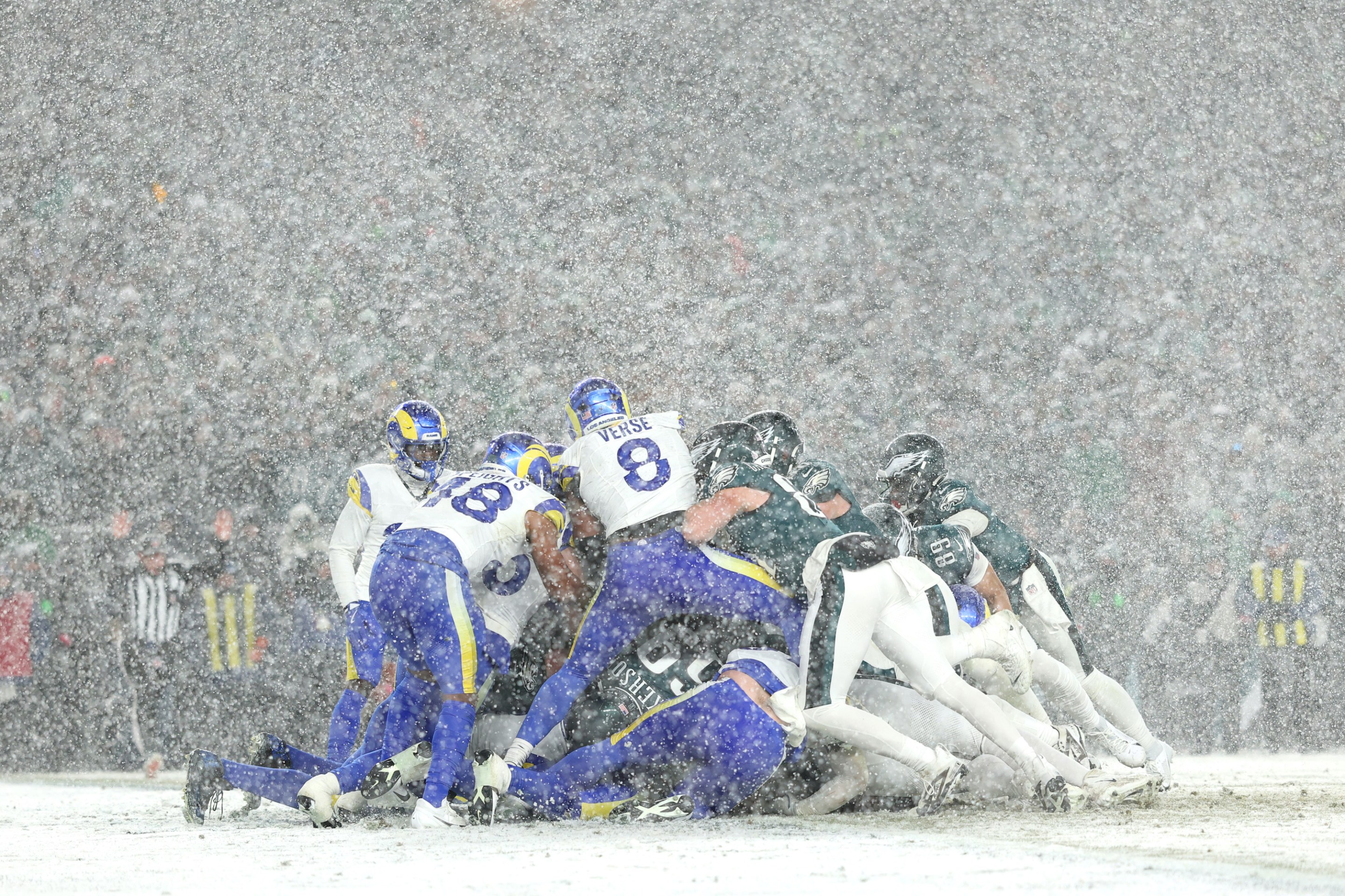 A pile of Rams and Eagles players in the snow.