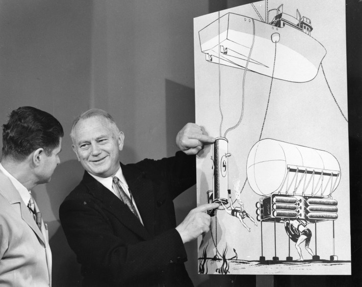 Al Behnke shows off a drawing to a colleague