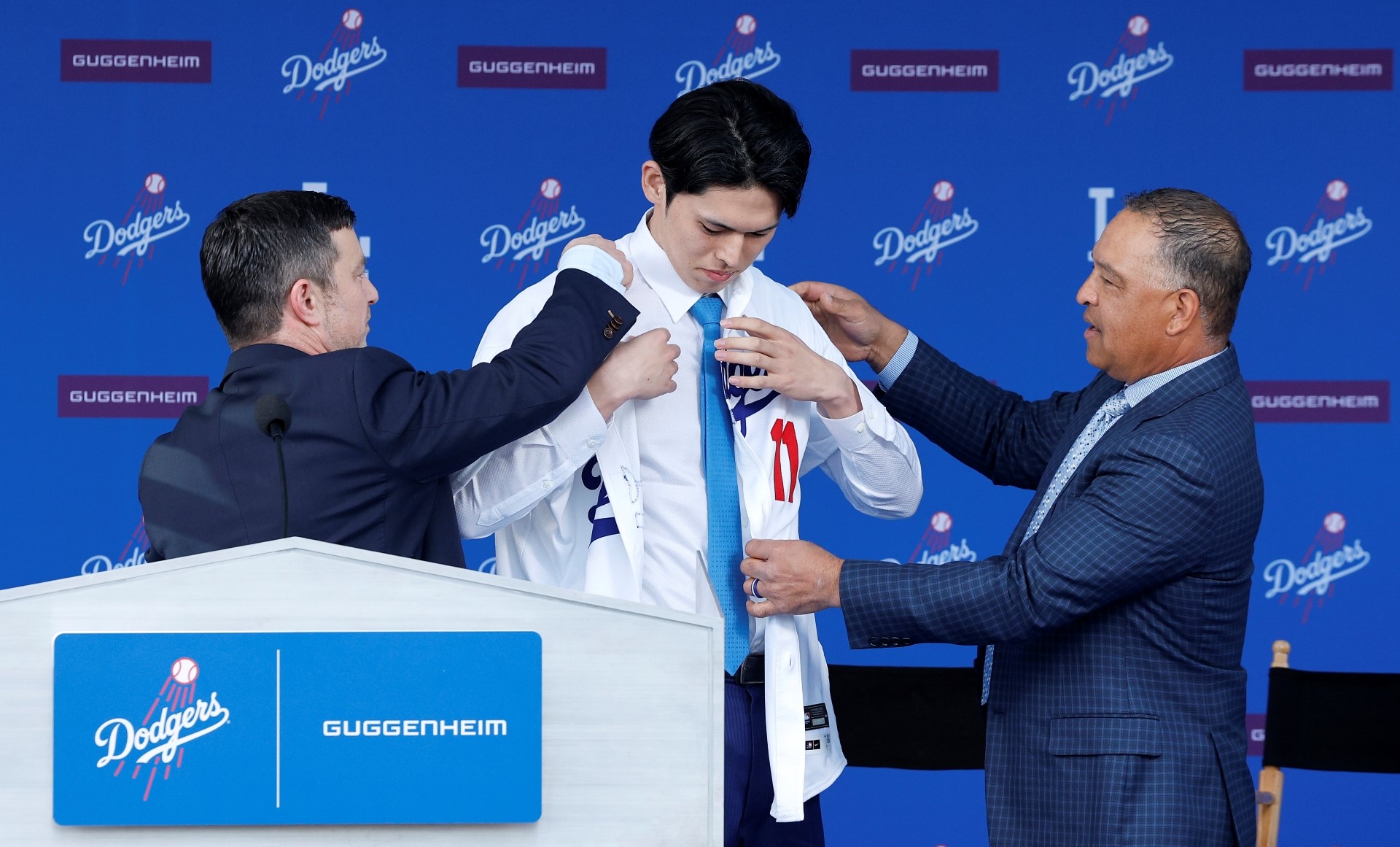 itcher Roki Sasaki puts on his jersey during a Los Angeles Dodgers press conference.