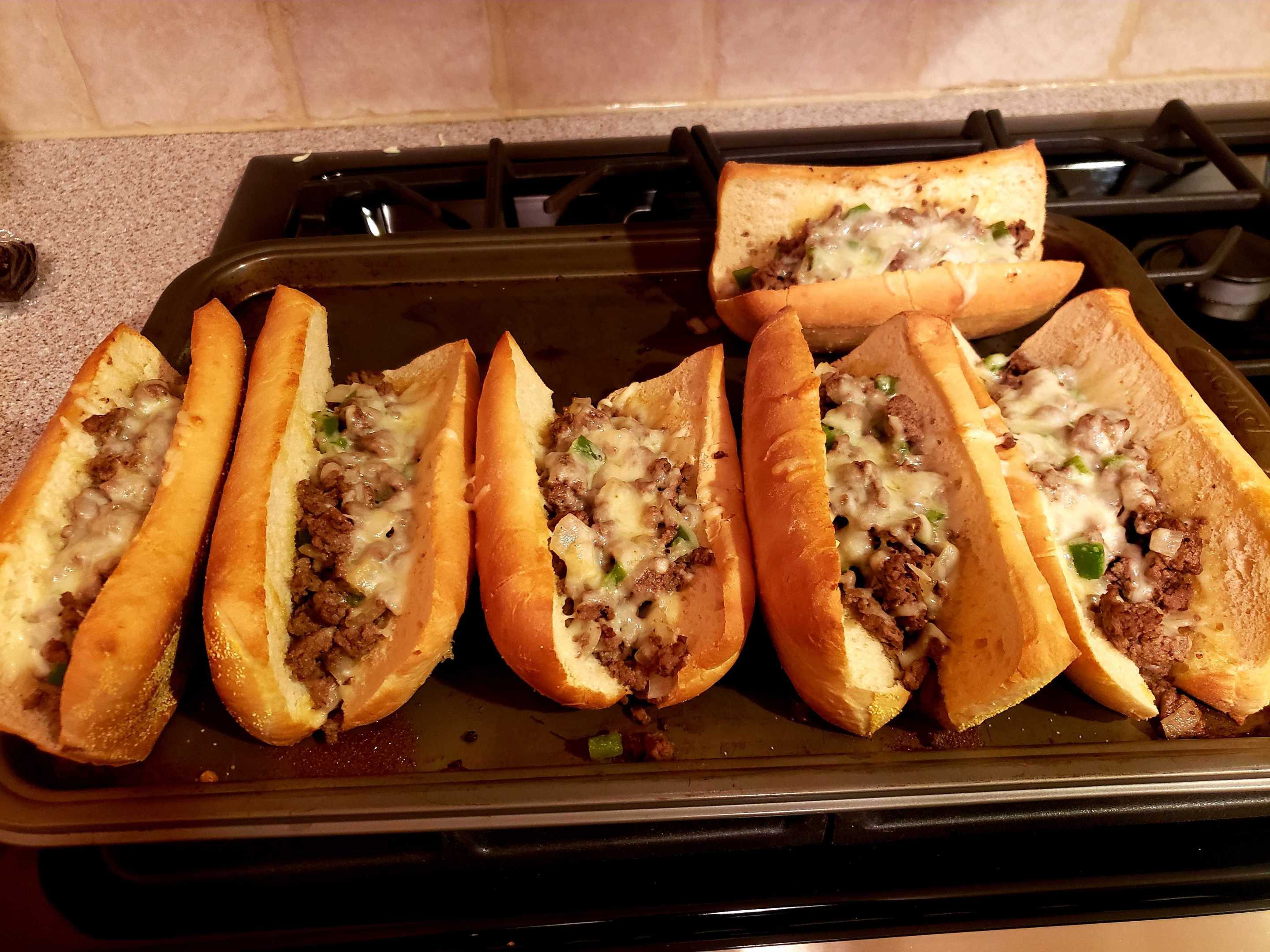 a set of homemade toasted subs with ground beef, cheese, green pepper and onion