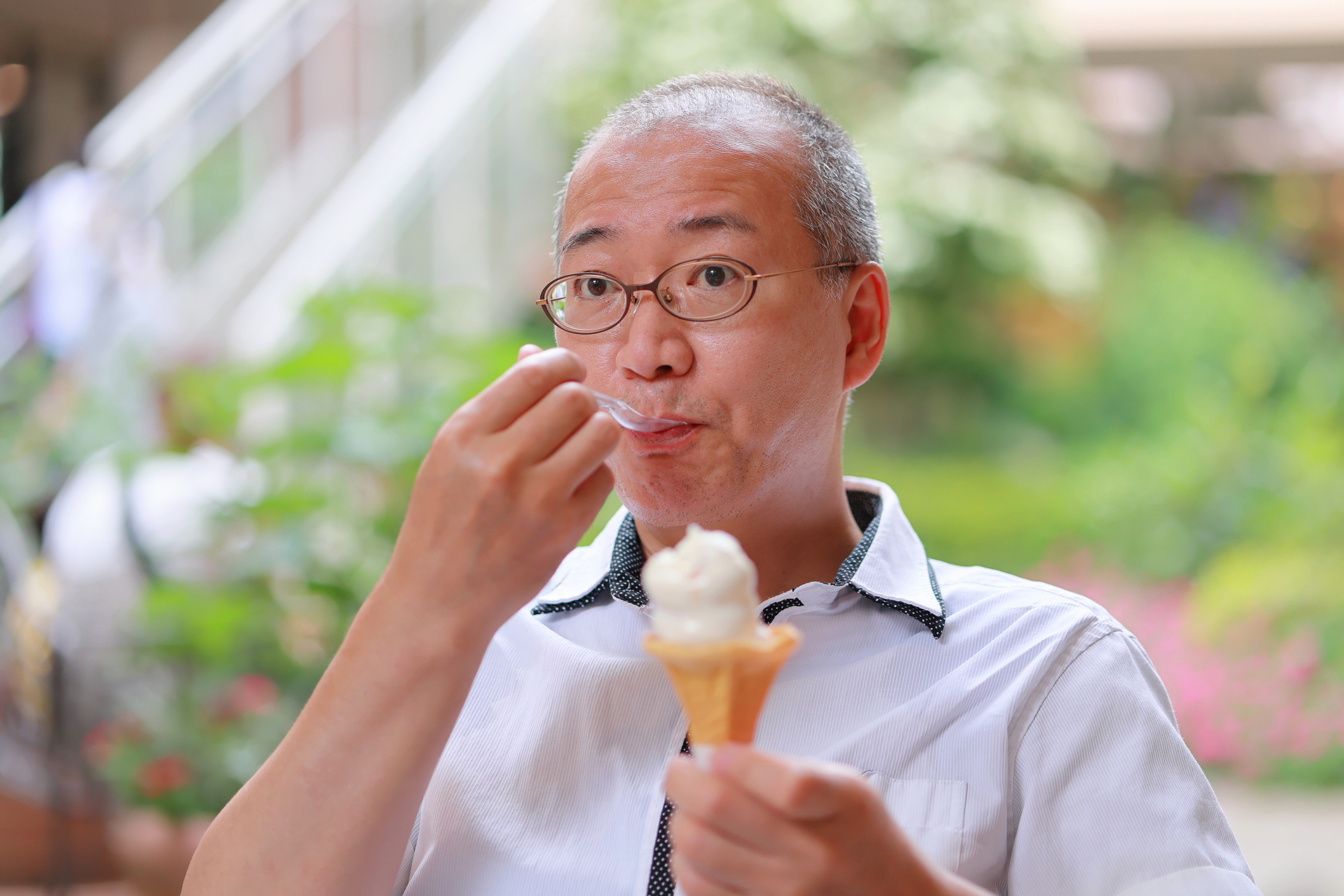 Man Eating Soft Ice Cream on Cone with Clear Plastic Spoon