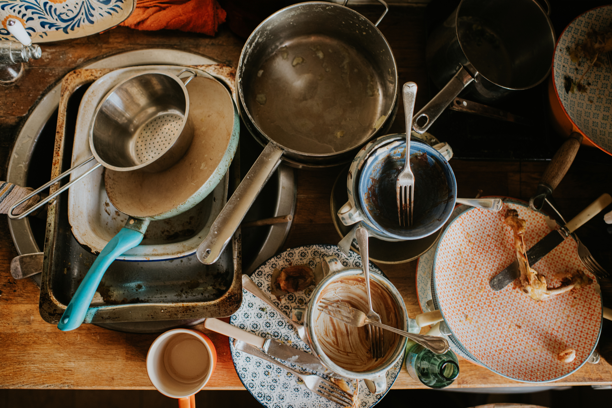 op down image of a pile of dirty dishes and saucepans sitting on a countertop in a kitchen