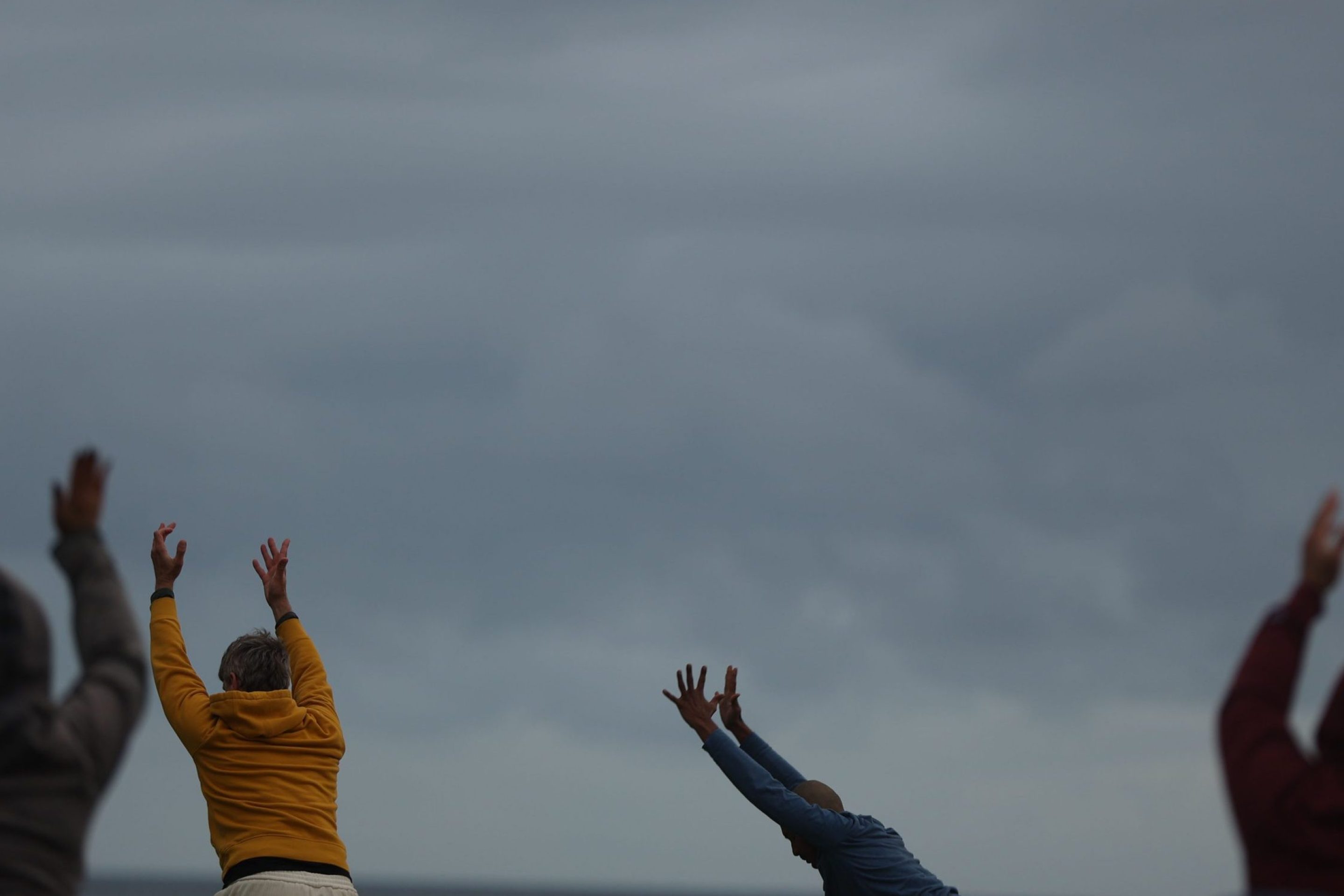 People stretch and raise their hands during an outside yoga session on Thursday, April 4, 2024 in Long Beach, CA.