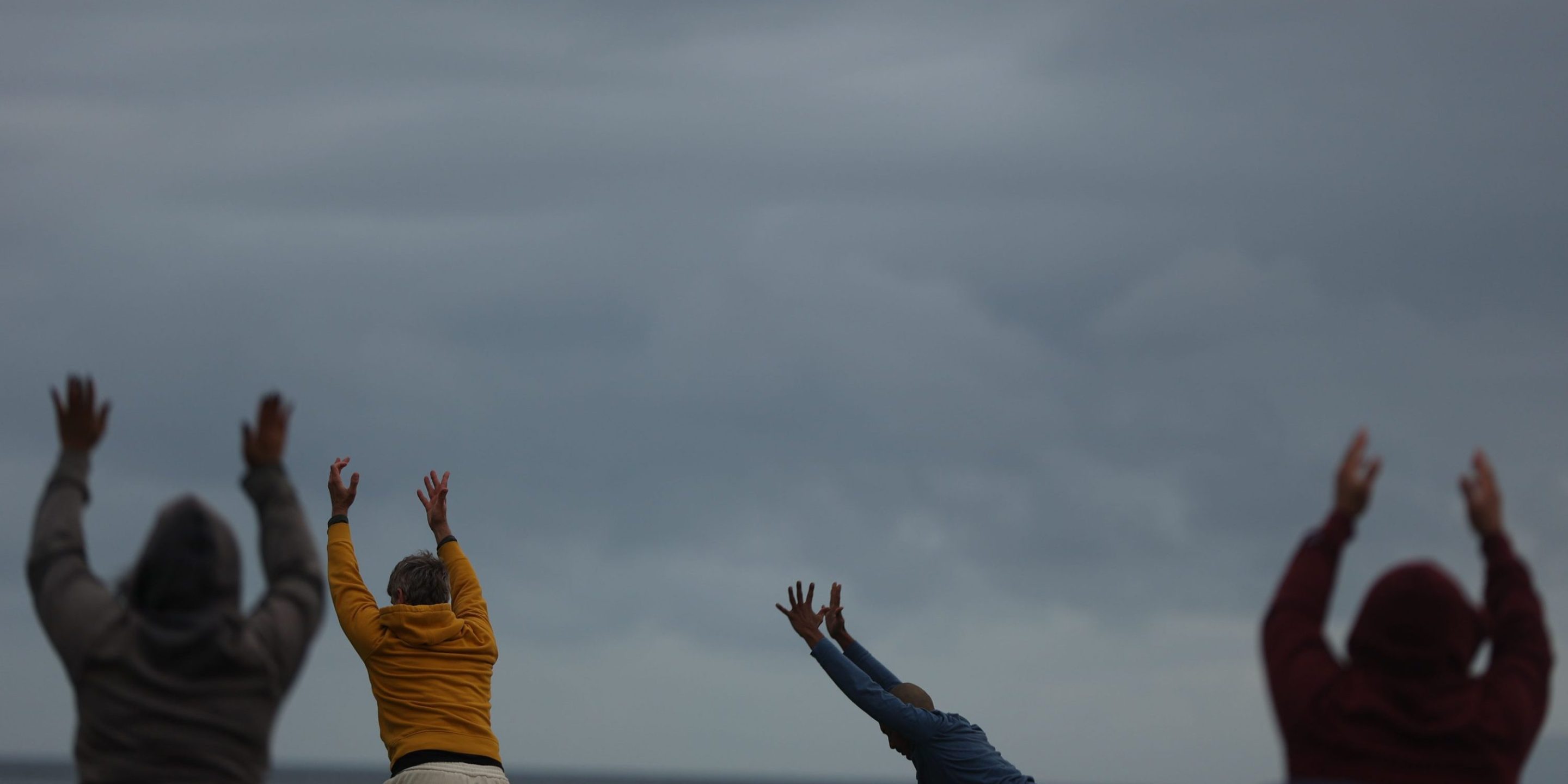 People stretch and raise their hands during an outside yoga session on Thursday, April 4, 2024 in Long Beach, CA.