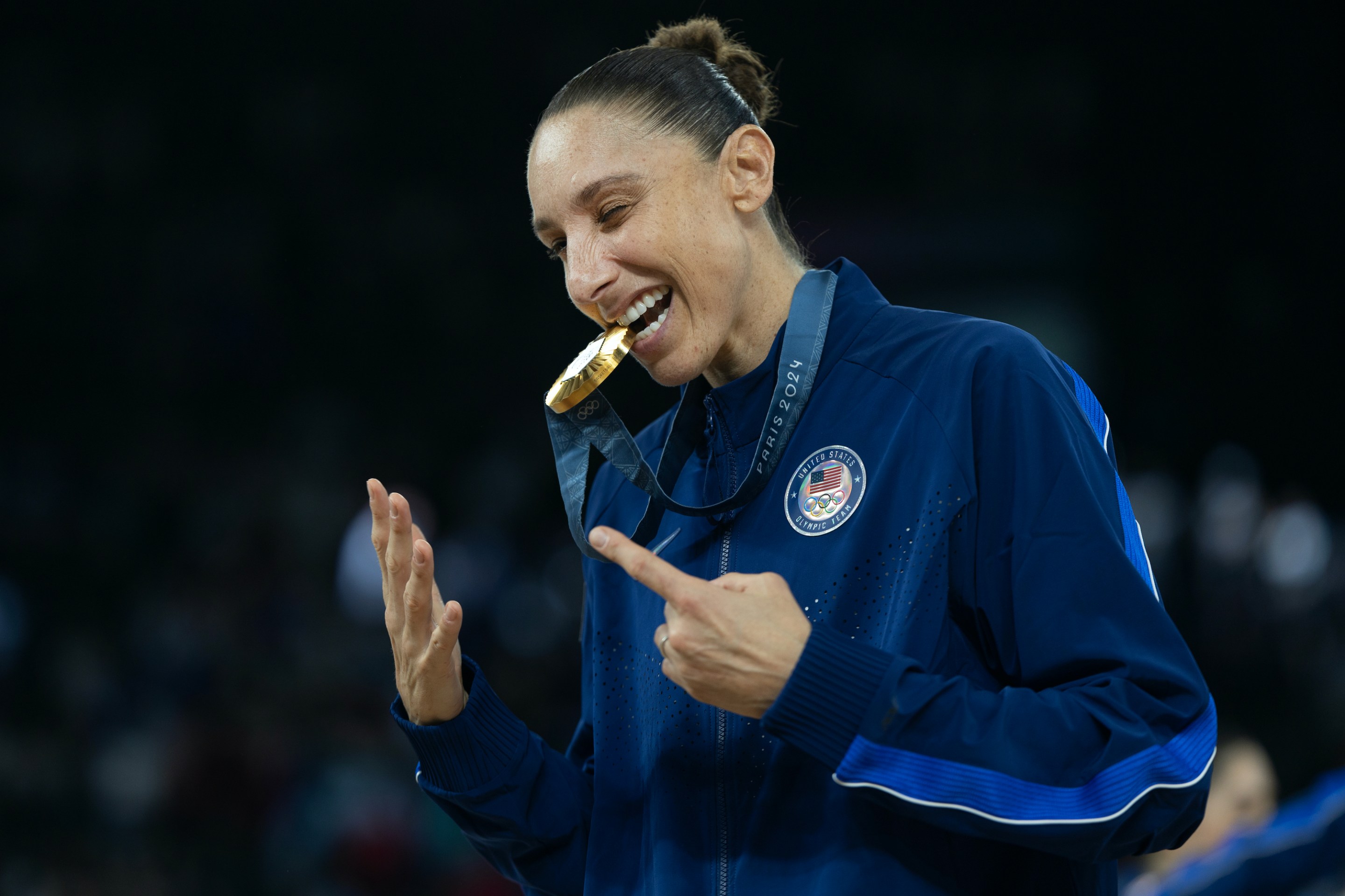 Diana Taurasi bites her sixth Olympic gold.