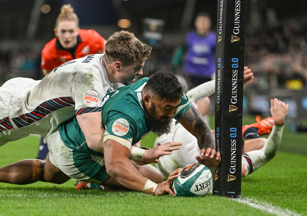 Bundee Aki of the Irish National Rugby team scores on a try while being tackled by Tommy Freeman of England during the first round of the Six Nations Rugby Championship