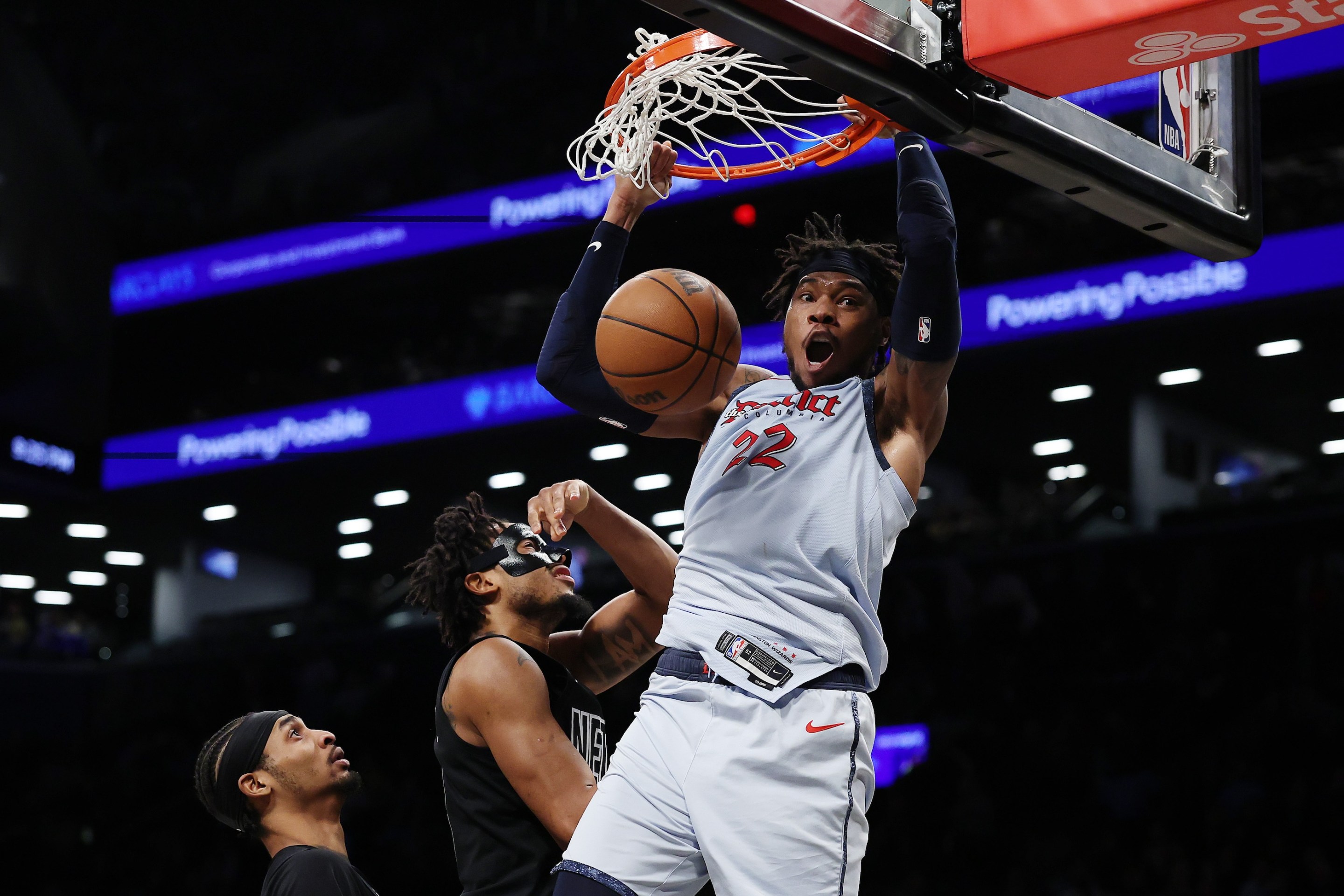 Richaun Holmes of the Washington Wizards reacts after dunking the ball as Nic Claxton of the Brooklyn Nets looks on.