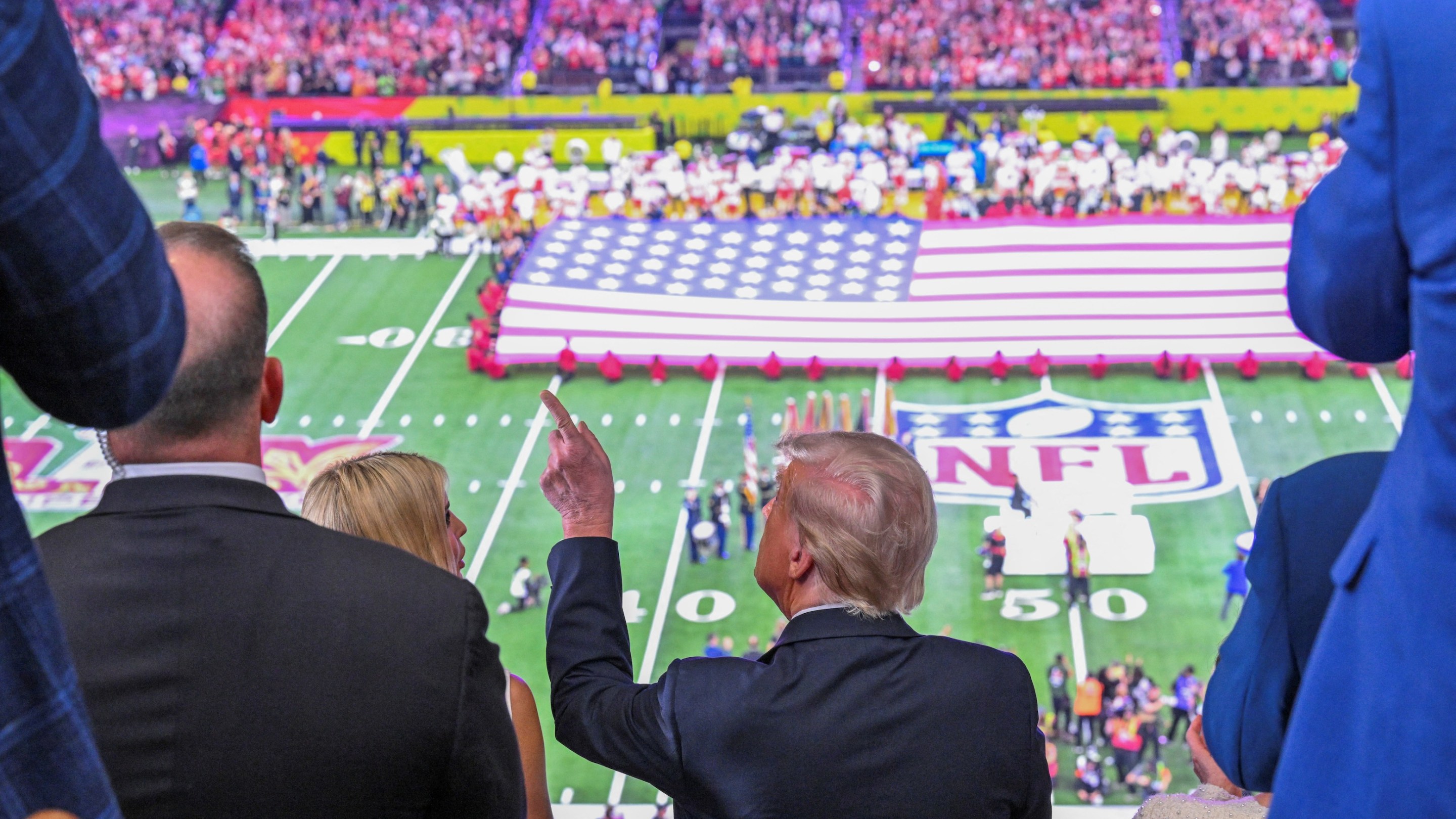 US President Donald Trump and Ivanka Trump (L) watch the pre-game show before Super Bowl LIX on February 9, 2025. His hair looks all fucked up; there's a huge American flag on the field.