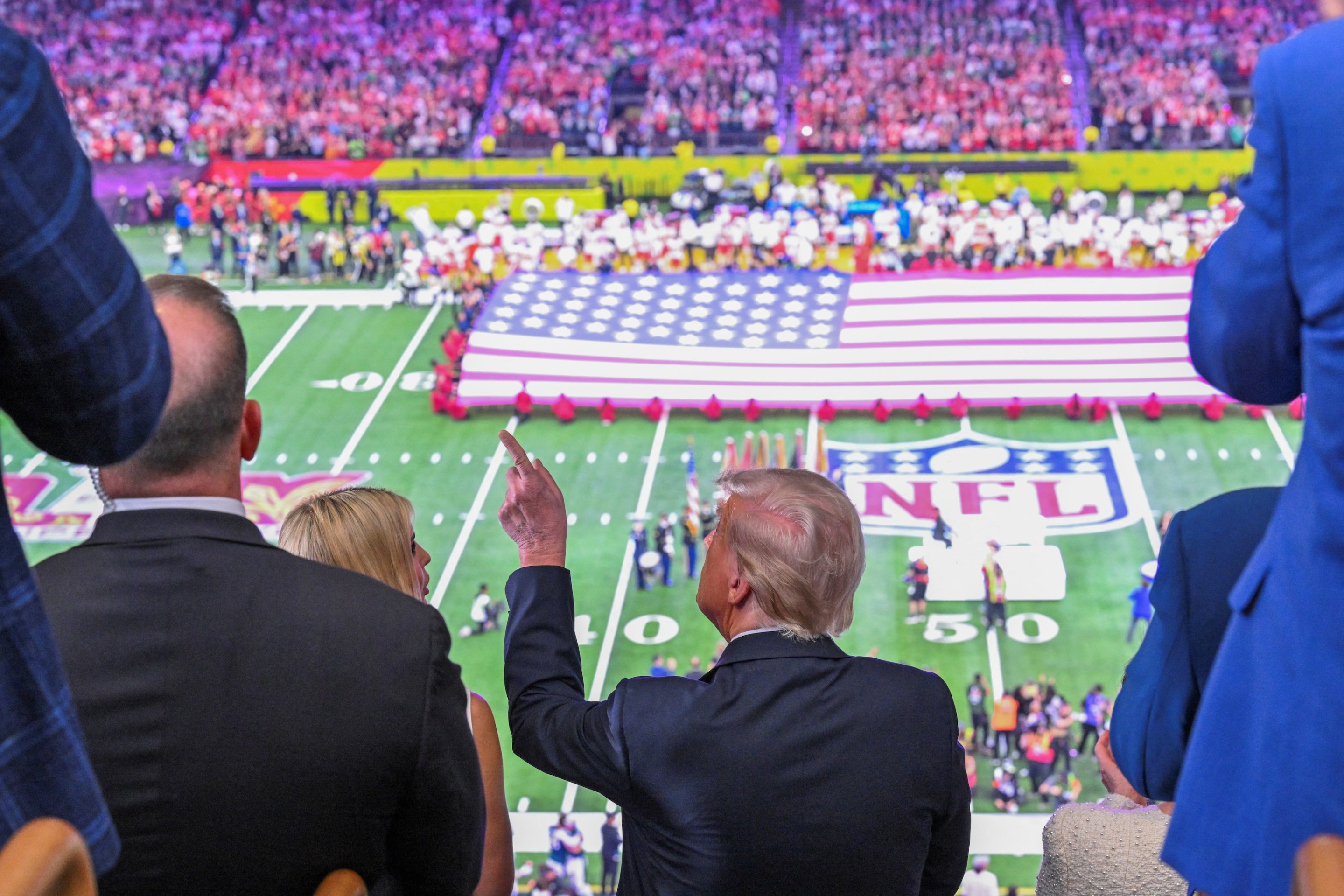 US President Donald Trump and Ivanka Trump (L) watch the pre-game show before Super Bowl LIX on February 9, 2025. His hair looks all fucked up; there's a huge American flag on the field.