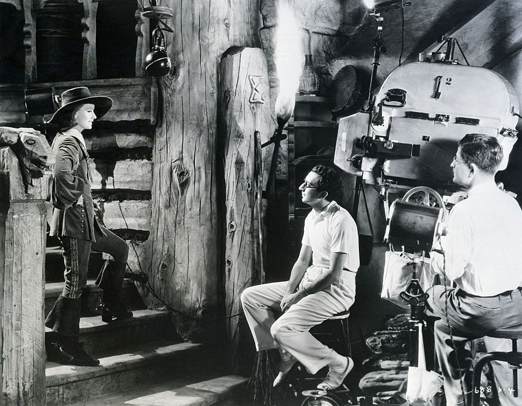 A camera operator stands by as director Rouben Mamoulian speaks with Greta Garbo.