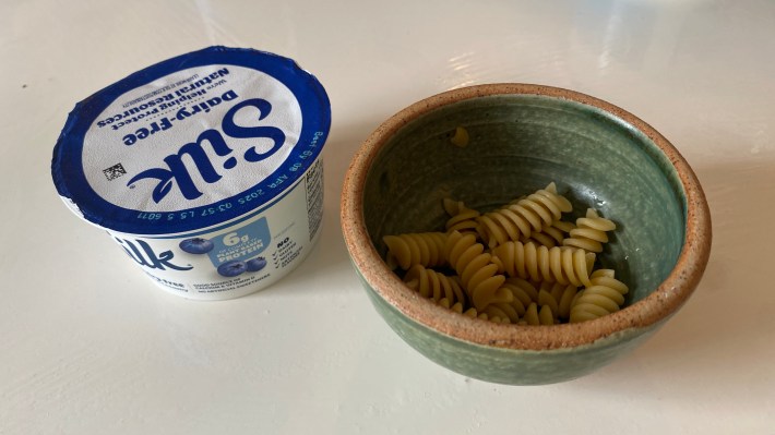 Uma foto de iogurte de mirtilo de soja de seda ao lado de uma pequena tigela de macarrão Rotini