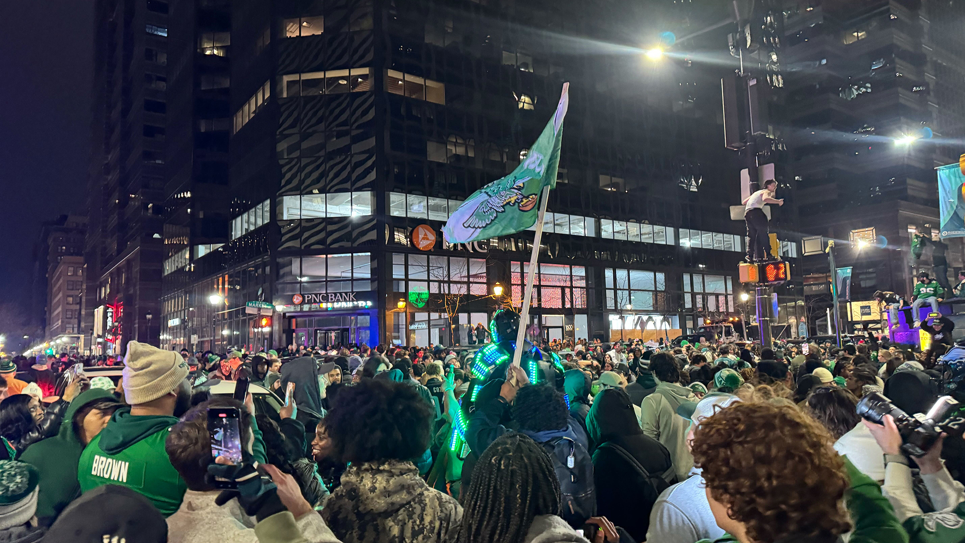 Eagles flag flying above a crowd of people that includes someone in a robot costume