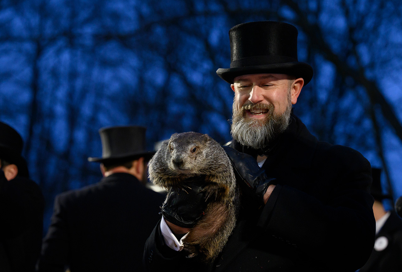 Groundhog handler AJ Dereume holds Punxsutawney Phil after he did not see his shadow predicting an early Spring during the 138th annual Groundhog Day festivities on Friday February 2, 2024 in Punxsutawney, Pennsylvania. Groundhog Day is a popular tradition in the United States and Canada. Over 40,000 people spent a night of revelry awaiting the sunrise and the groundhog's exit from his winter den. If Punxsutawney Phil sees his shadow he regards it as an omen of six more weeks of bad weather and returns to his den. Dereume is wearing a top hat and has a grey beard and he's in a black coat.