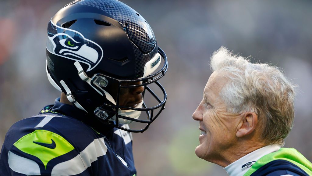Geno Smith #7 of the Seattle Seahawks meets with head coach Pete Carroll in the third quarter against the Las Vegas Raiders at Lumen Field on November 27, 2022 in Seattle, Washington.