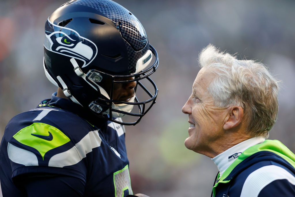 Geno Smith #7 of the Seattle Seahawks meets with head coach Pete Carroll in the third quarter against the Las Vegas Raiders at Lumen Field on November 27, 2022 in Seattle, Washington.