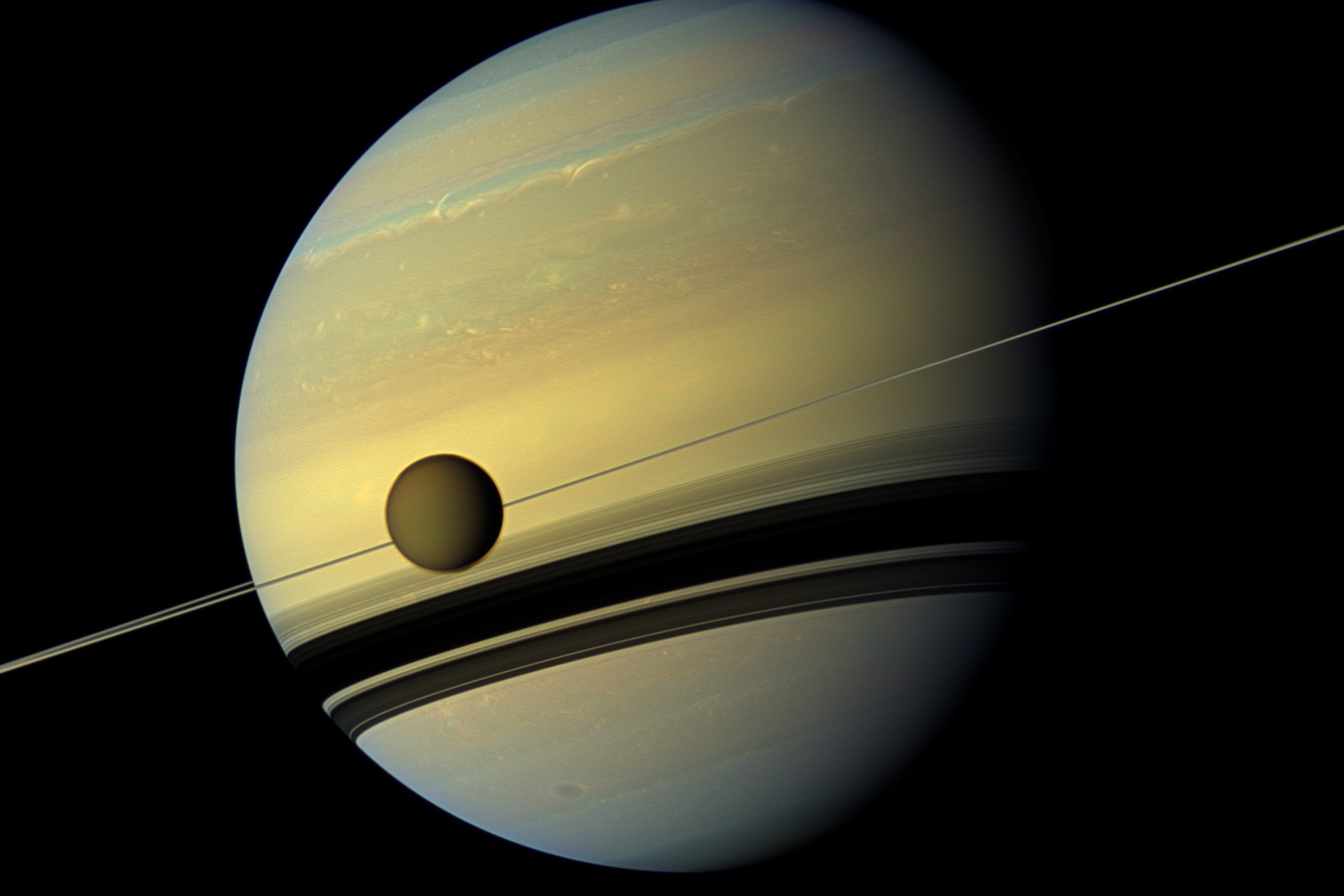 A giant of a moon appears before a giant of a planet undergoing seasonal changes in this natural color view of Titan and Saturn from NASA's Cassini spacecraft. (Photo by: Universal History Archive/Universal Images Group via Getty Images)