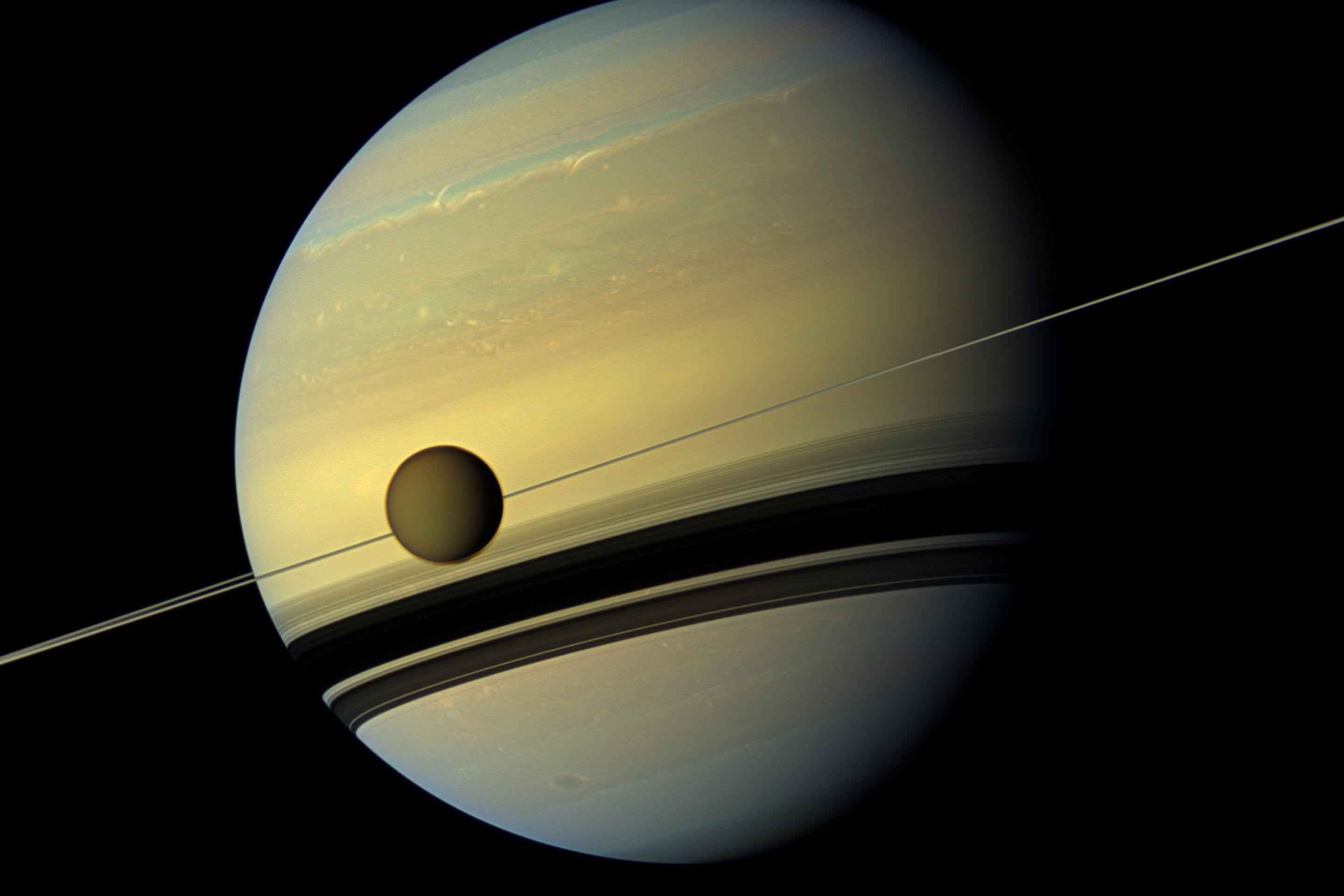 A giant of a moon appears before a giant of a planet undergoing seasonal changes in this natural color view of Titan and Saturn from NASA's Cassini spacecraft. (Photo by: Universal History Archive/Universal Images Group via Getty Images)