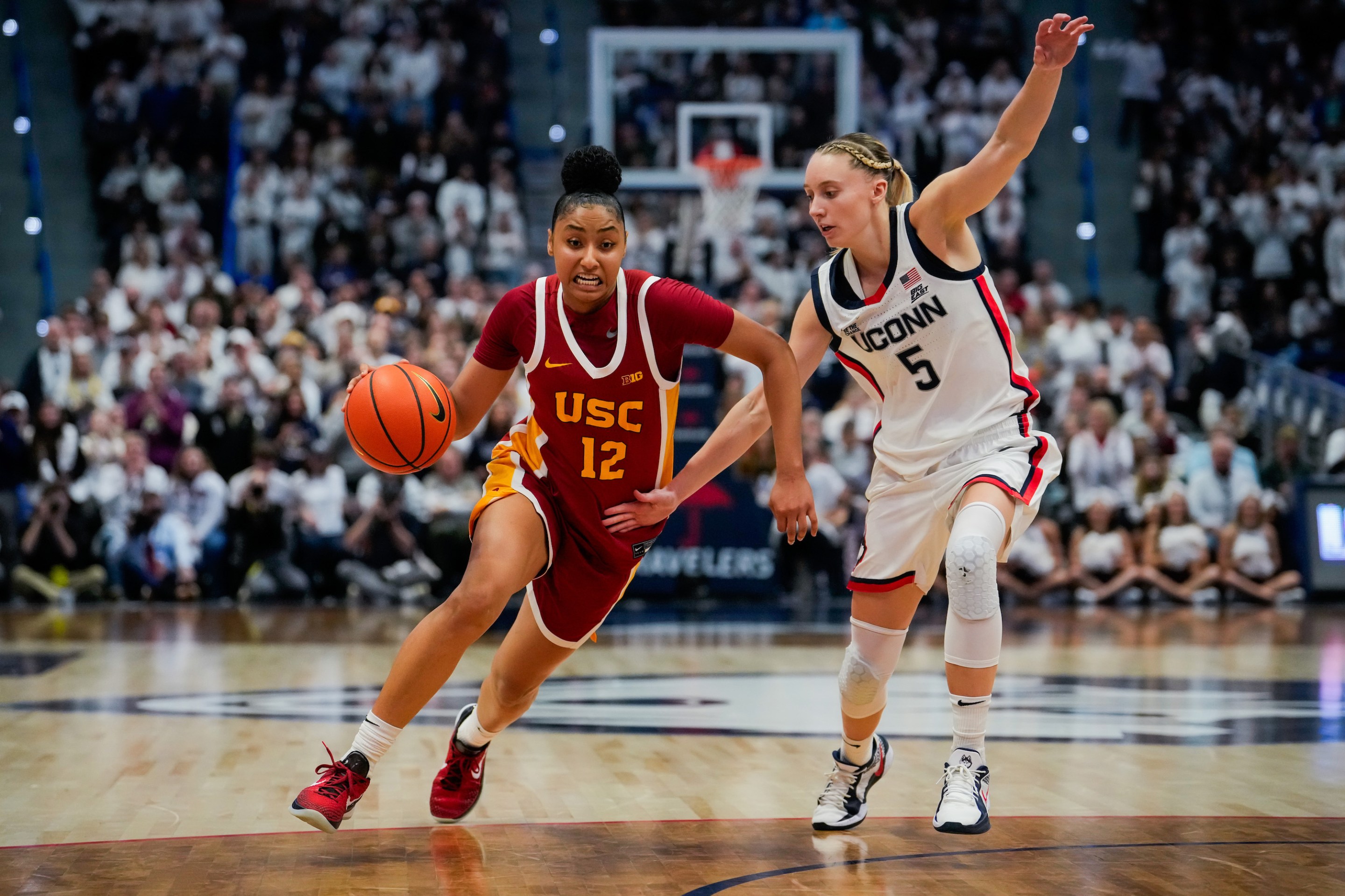 JuJu Watkins #12 of the USC Trojans is defended by Paige Bueckers #5 of the Connecticut Huskies during the second half of an NCAA women's basketball game at the XL Center on December 21, 2024 in Hartford, Connecticut.