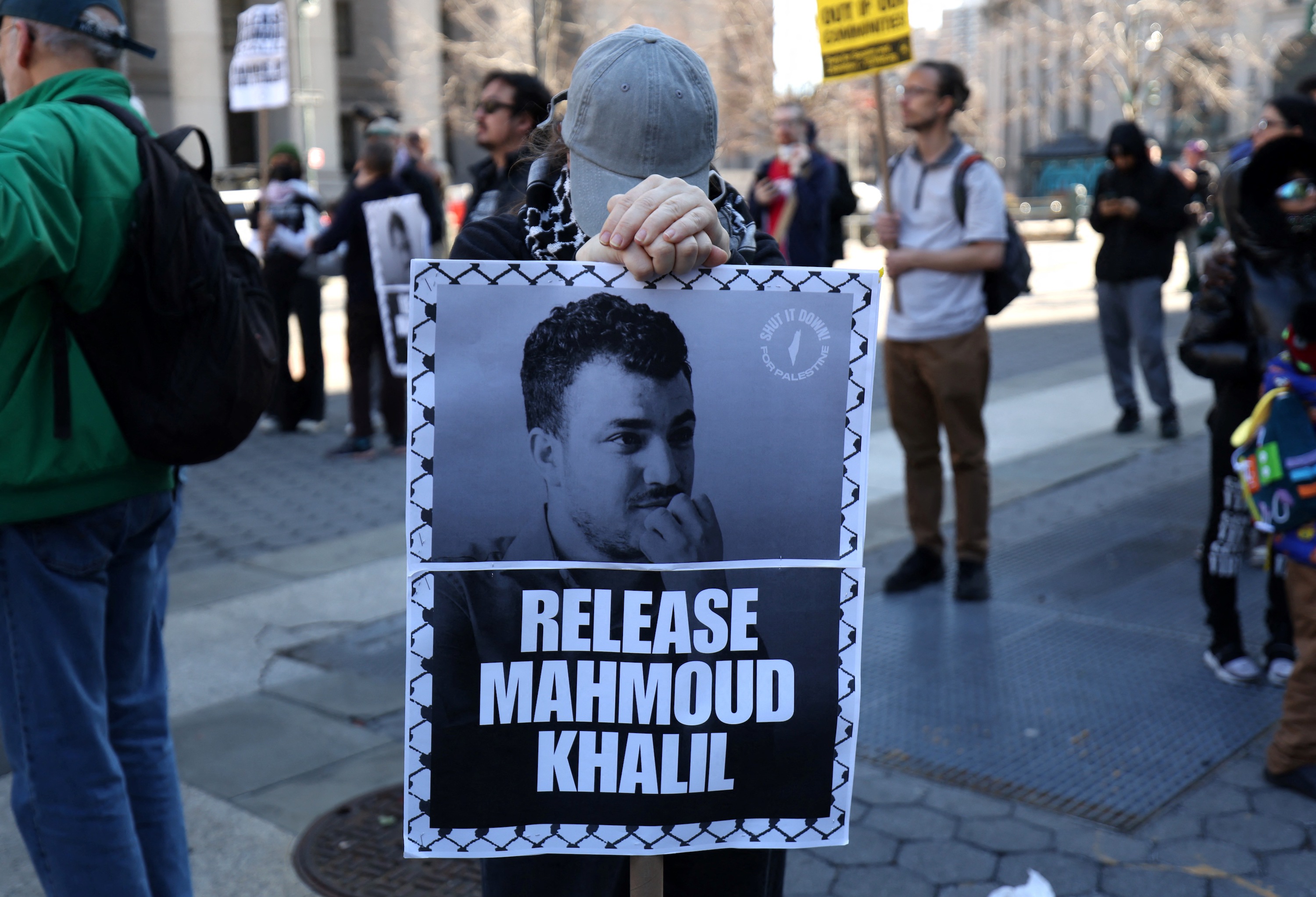 A protestor with a sign that reads "Release Mahmoud Khalil."