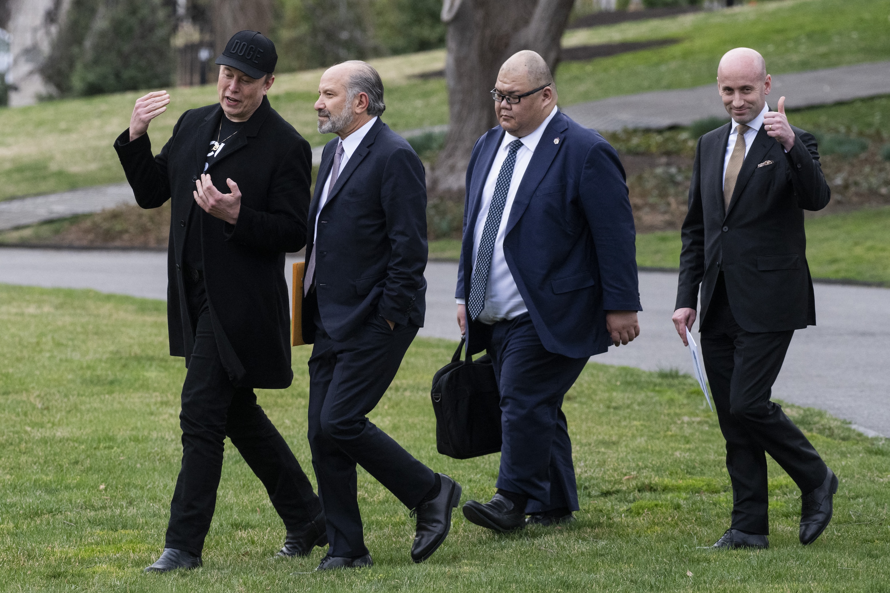 Elon Musk chats with US Secretary of Commerce Howard Lutnick as they walk with White House Communications Director Steven Cheung and White House deputy chief of staff for policy and US homeland security advisor Stephen Miller on the south lawn of the White House. Everyone absolutely looks like shit.