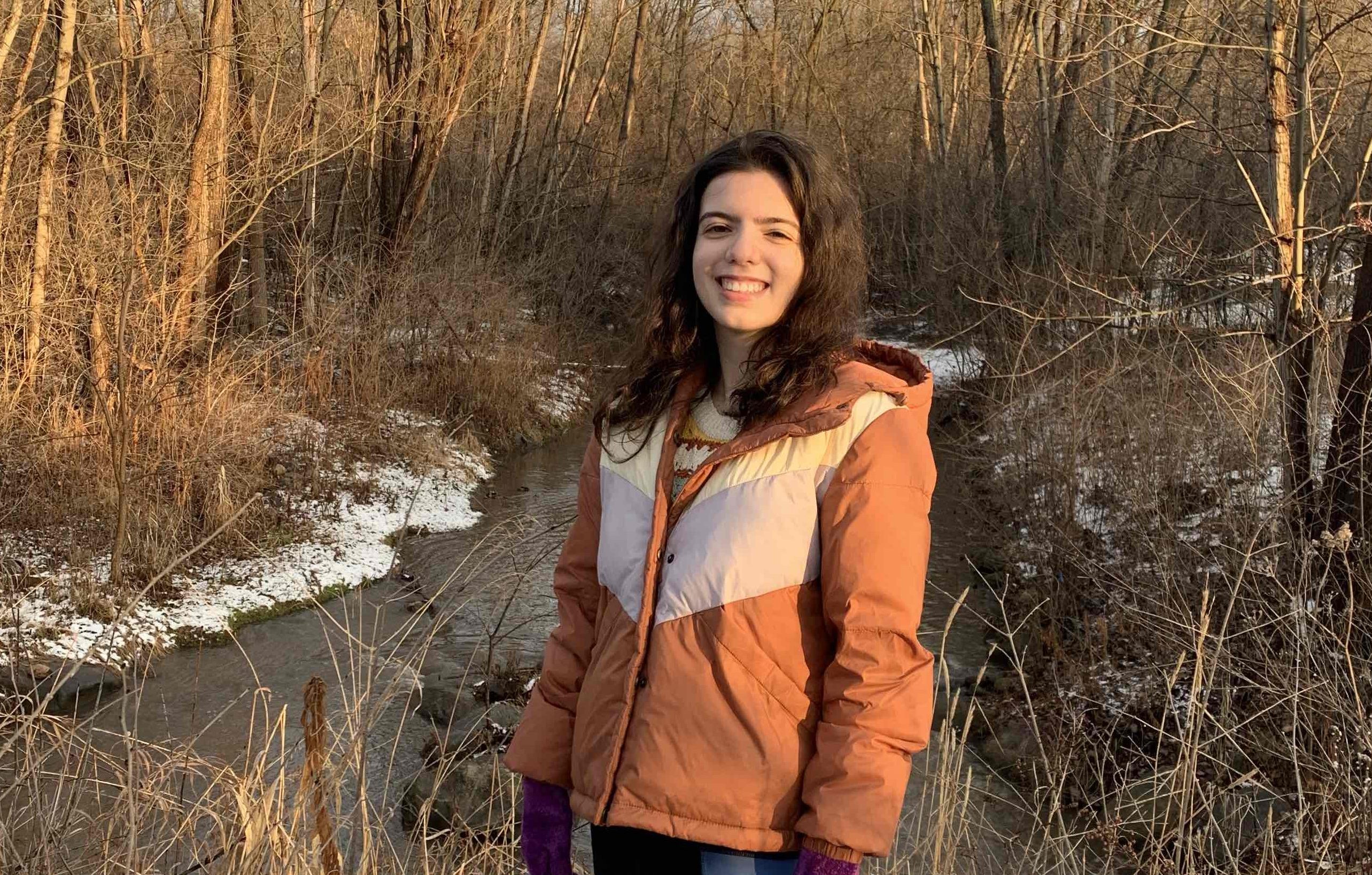 a photo of Veronica Correa, a fired EPA public affairs specialist, standing in snowy woods by a stream