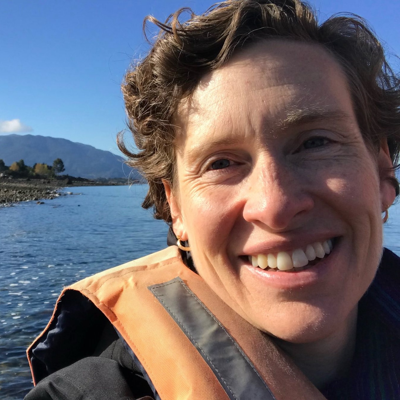 a selfie of Sarah Cooley, the former director of NOAA's ocean acidification program, with an orange life vest on a river