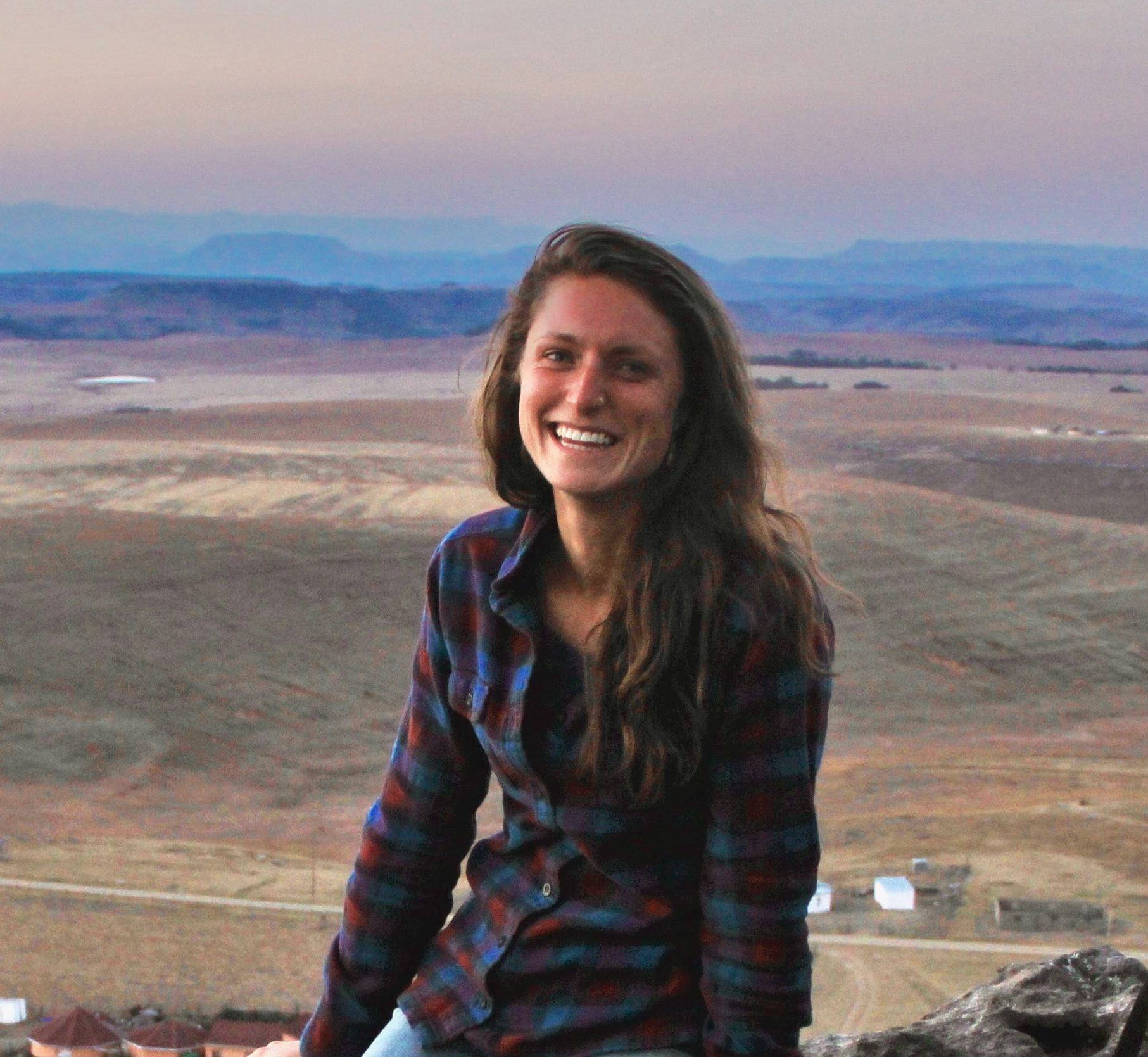 A photo of Jules Reynolds, a fired USDA program coordinator, sitting near a valley of farmland