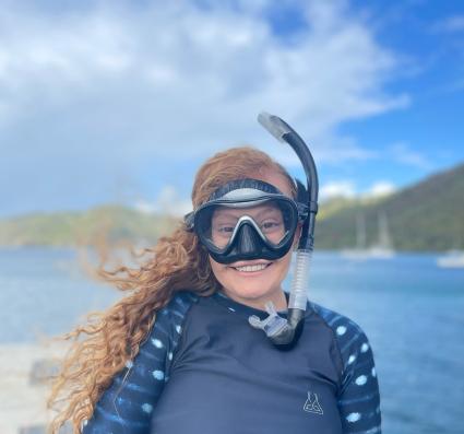 A photo of Madyson Miller, a fired program analyst, wearing a wetsuit patterned like a whale shark and a snorkel.