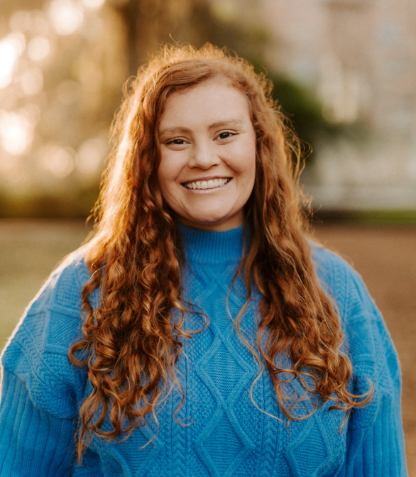 A headshot of Madyson Miller, a fired NOAA program analyst, in a blue sweater and golden light