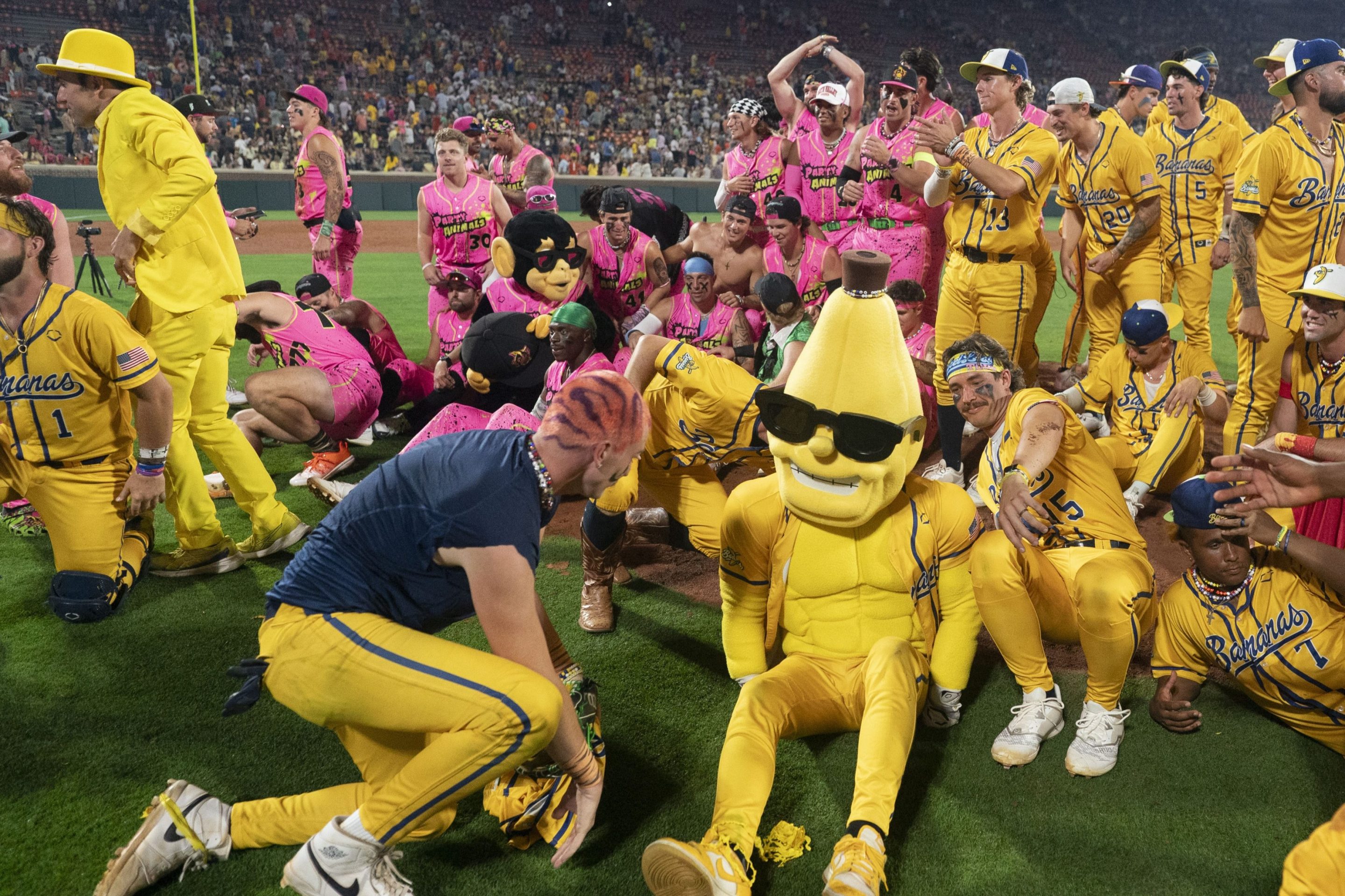 The Savannah Bananas players and Party Animals players get up after making a group photo after a game